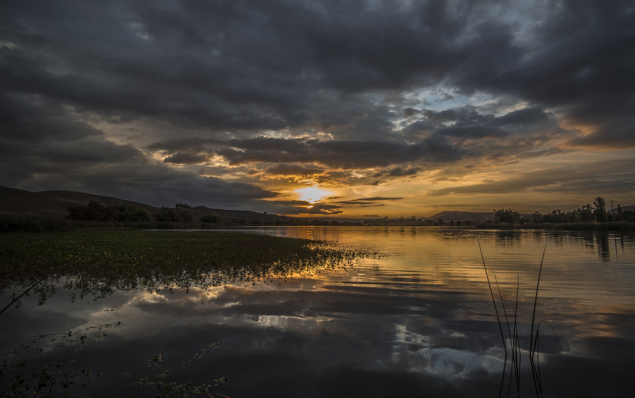 Sunset over a lake with dark clouds HD Wallpaper