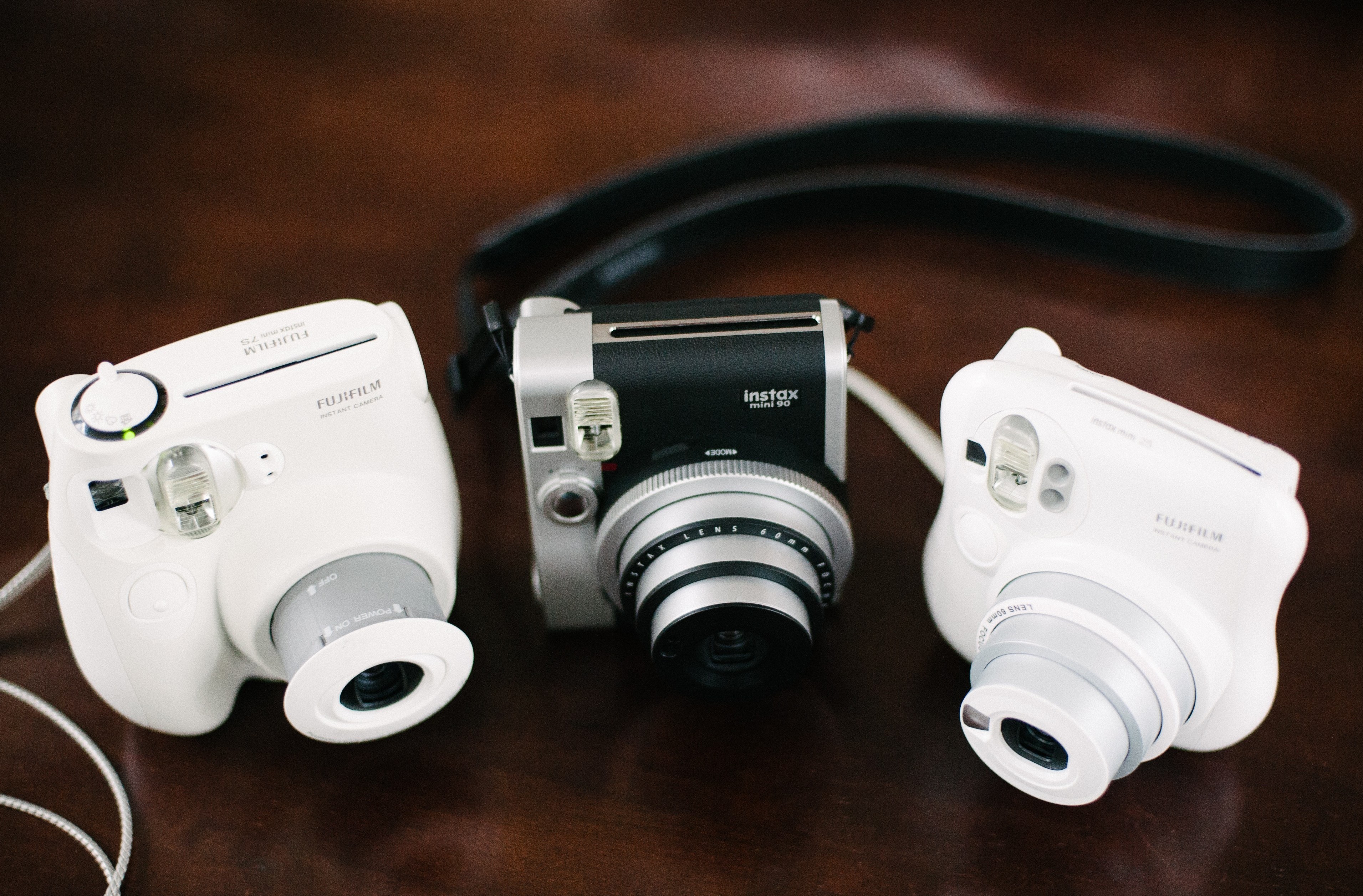 Three Fujifilm Instax Mini cameras on a wooden surface HD Wallpaper