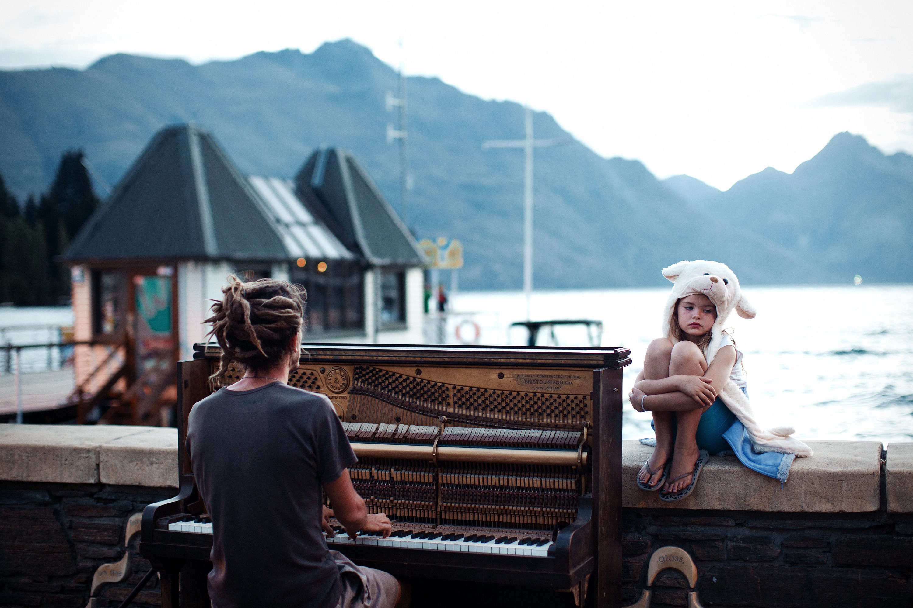 Man playing piano with girl in sheep hat by lake HD Wallpaper