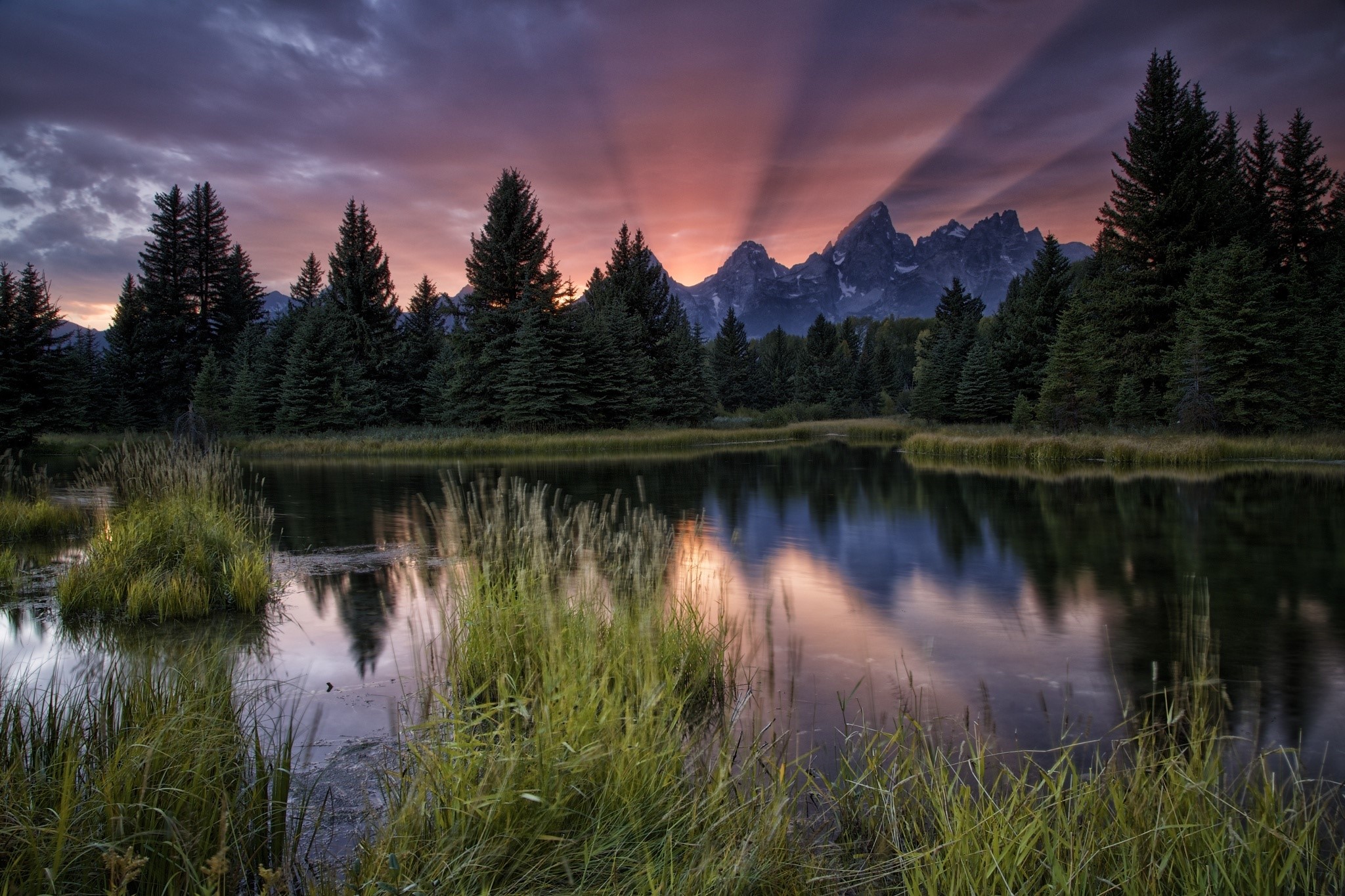 Sunbeams over mountains reflected in a lake at sunset HD Wallpaper