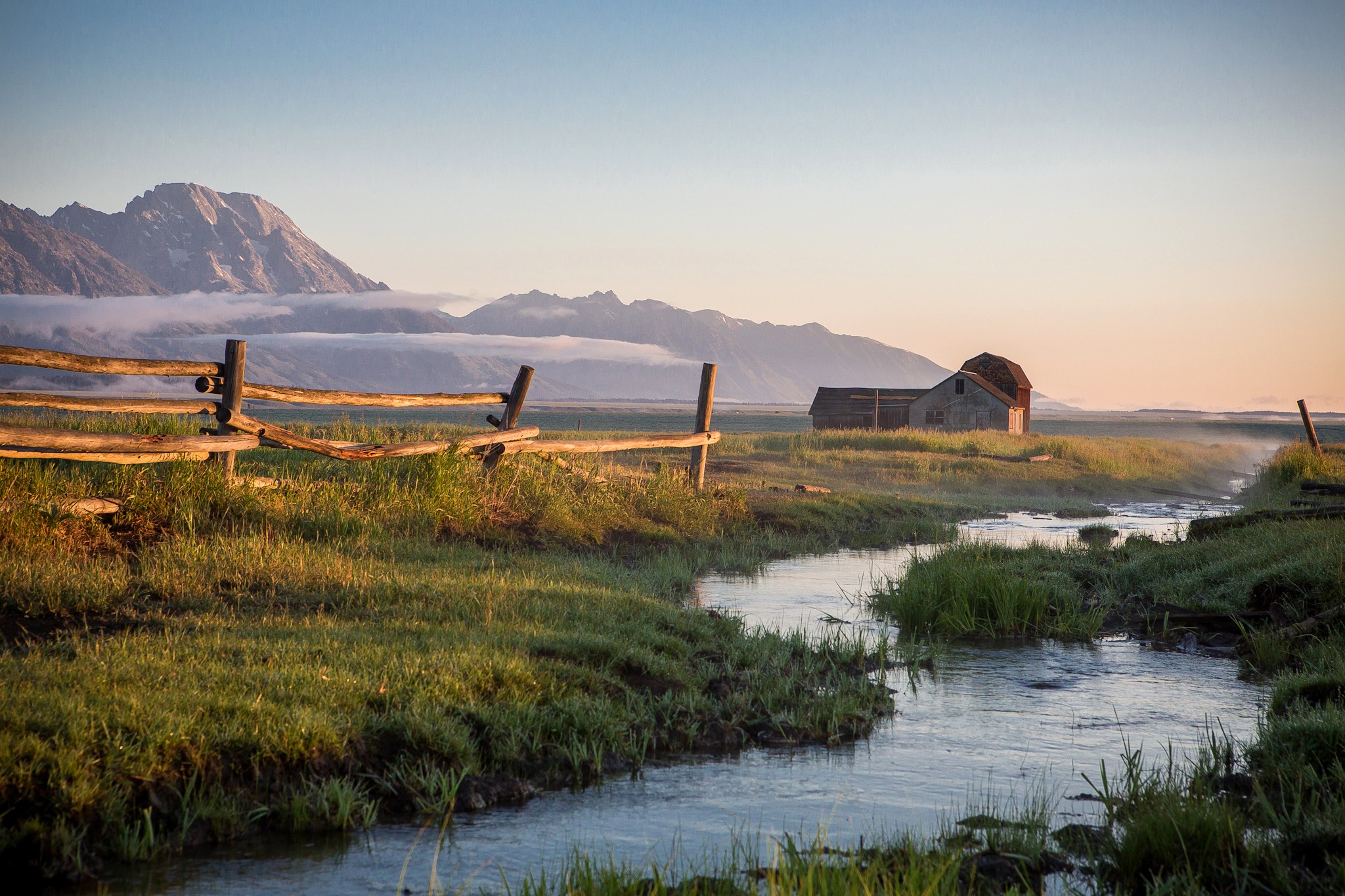 Barn and fence by mountains with fog and stream HD Wallpaper