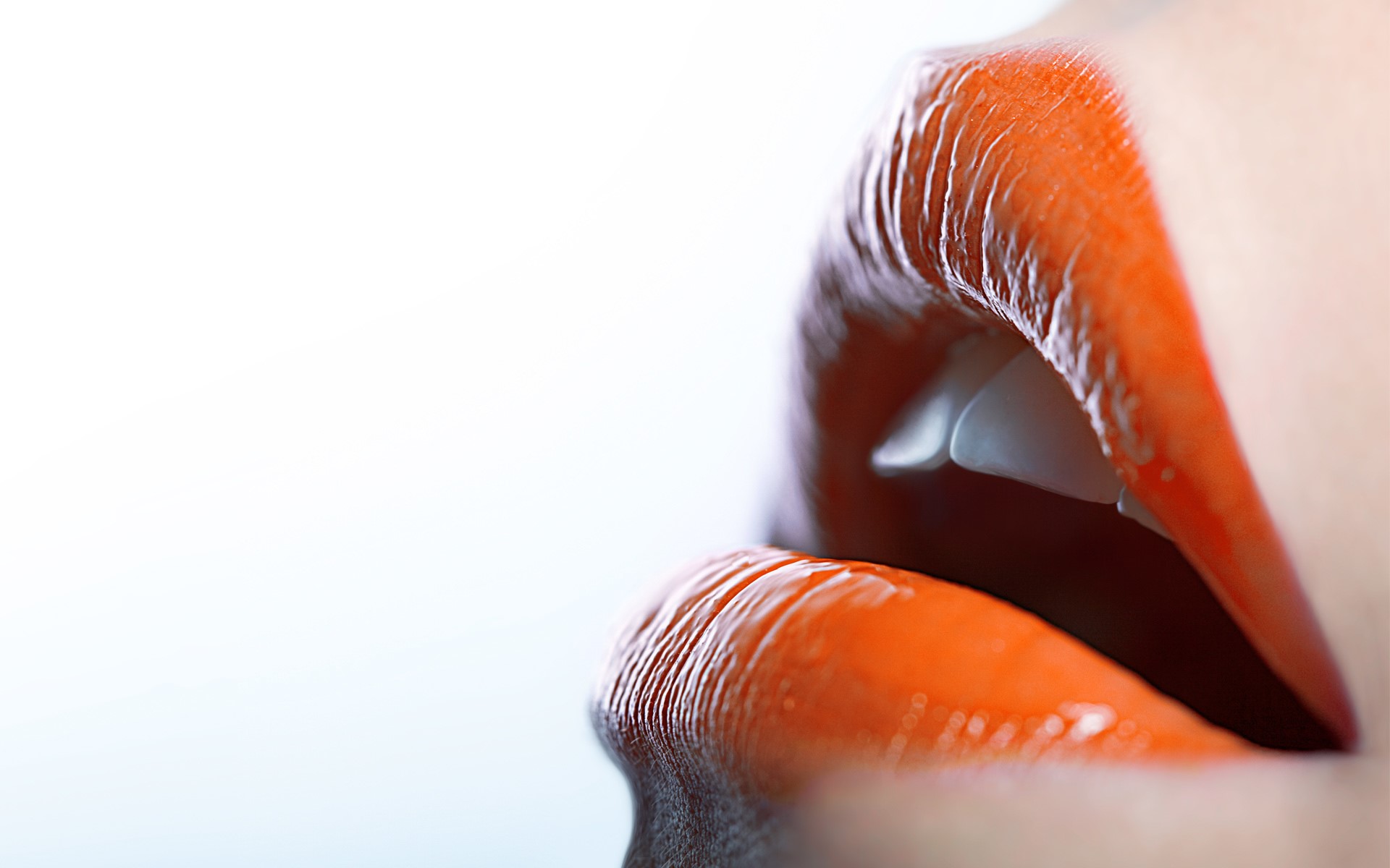 Close-up of glossy orange lips with teeth showing HD Wallpaper