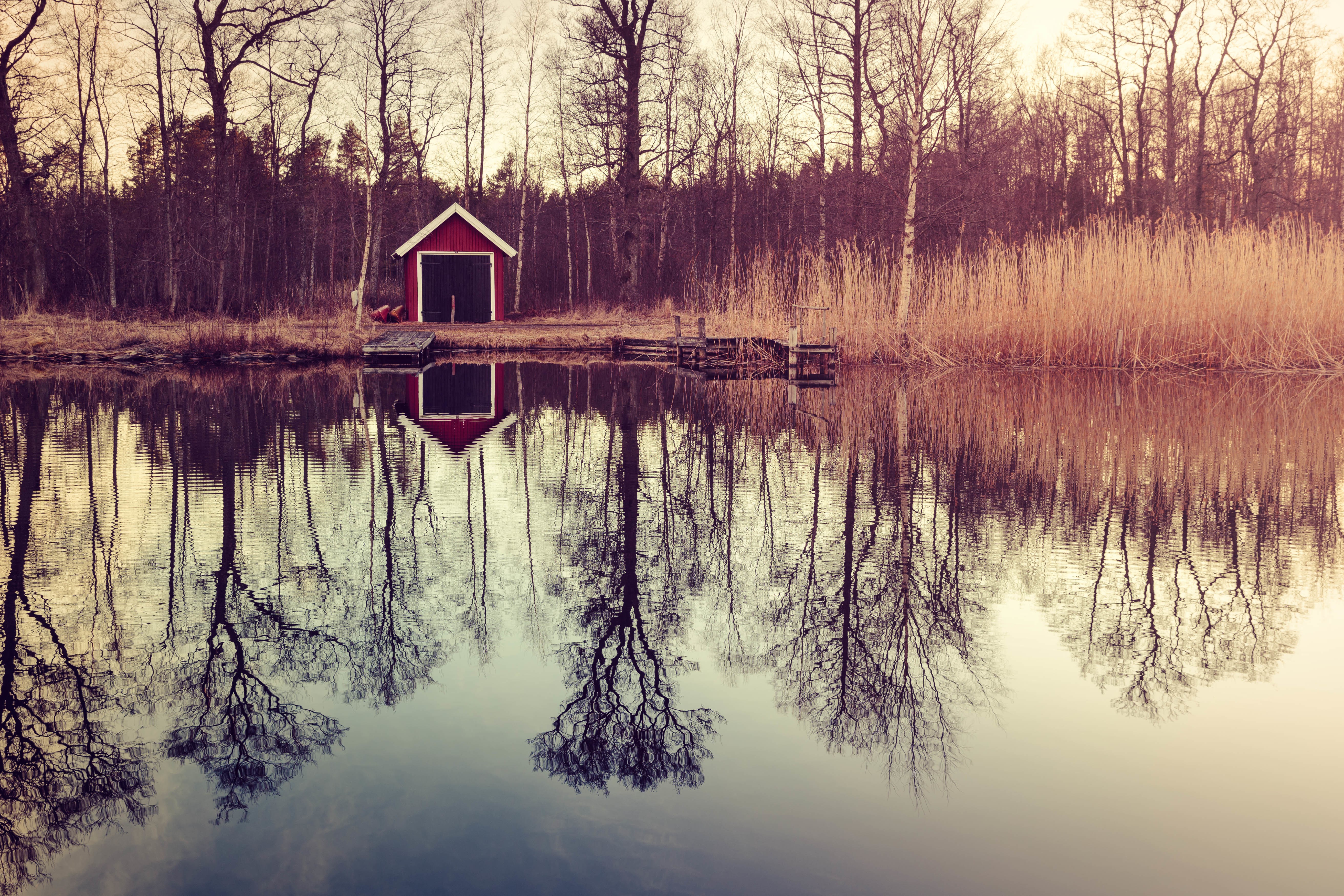 Red boathouse reflected in a lake with trees HD Wallpaper