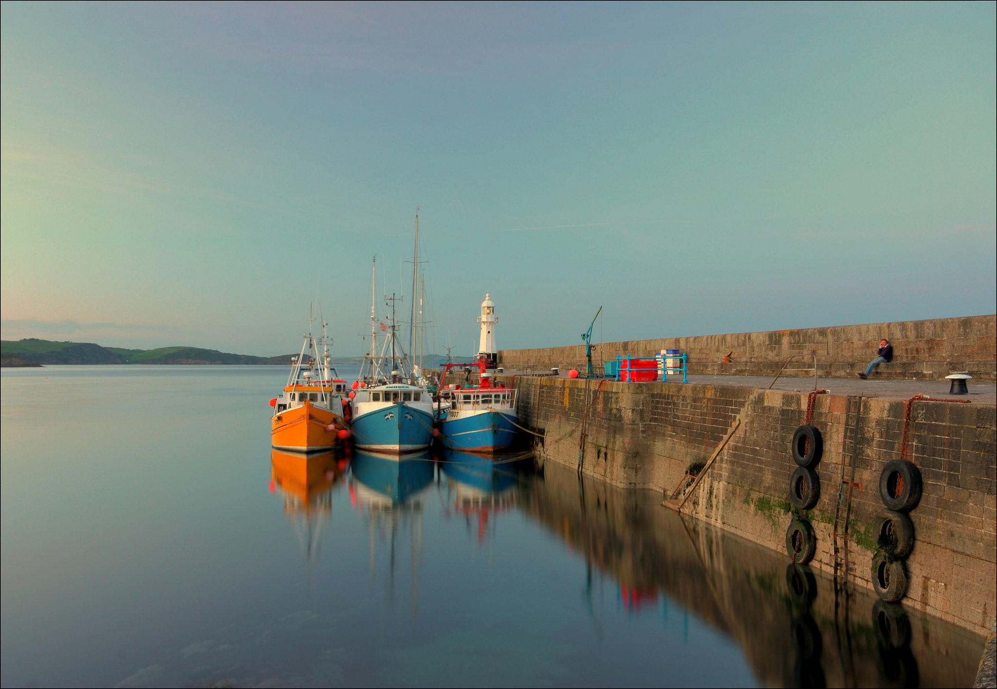 Fishing boats docked at a harbor with a lighthouse HD Wallpaper