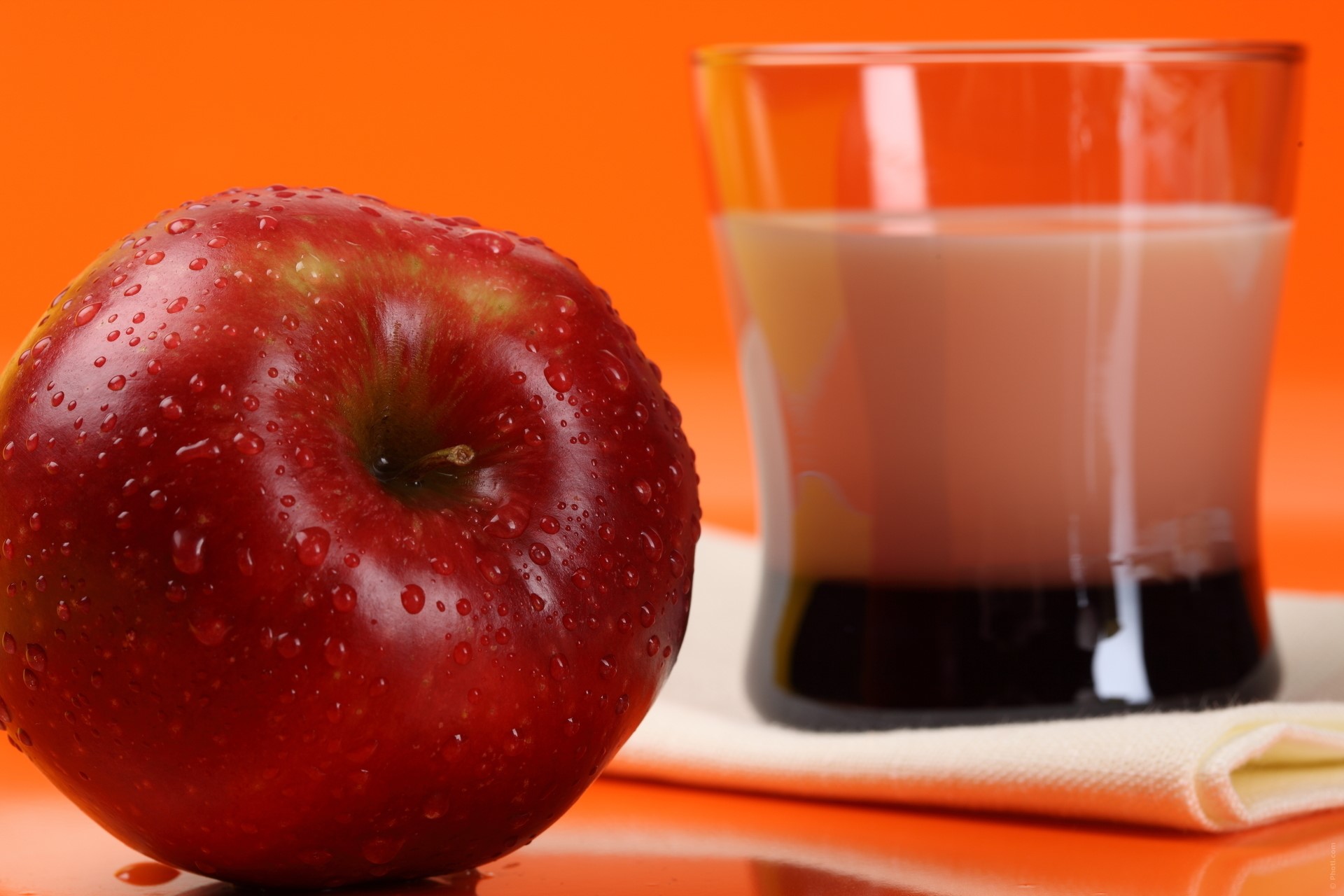 Red apple and glass of drink on orange background HD Wallpaper