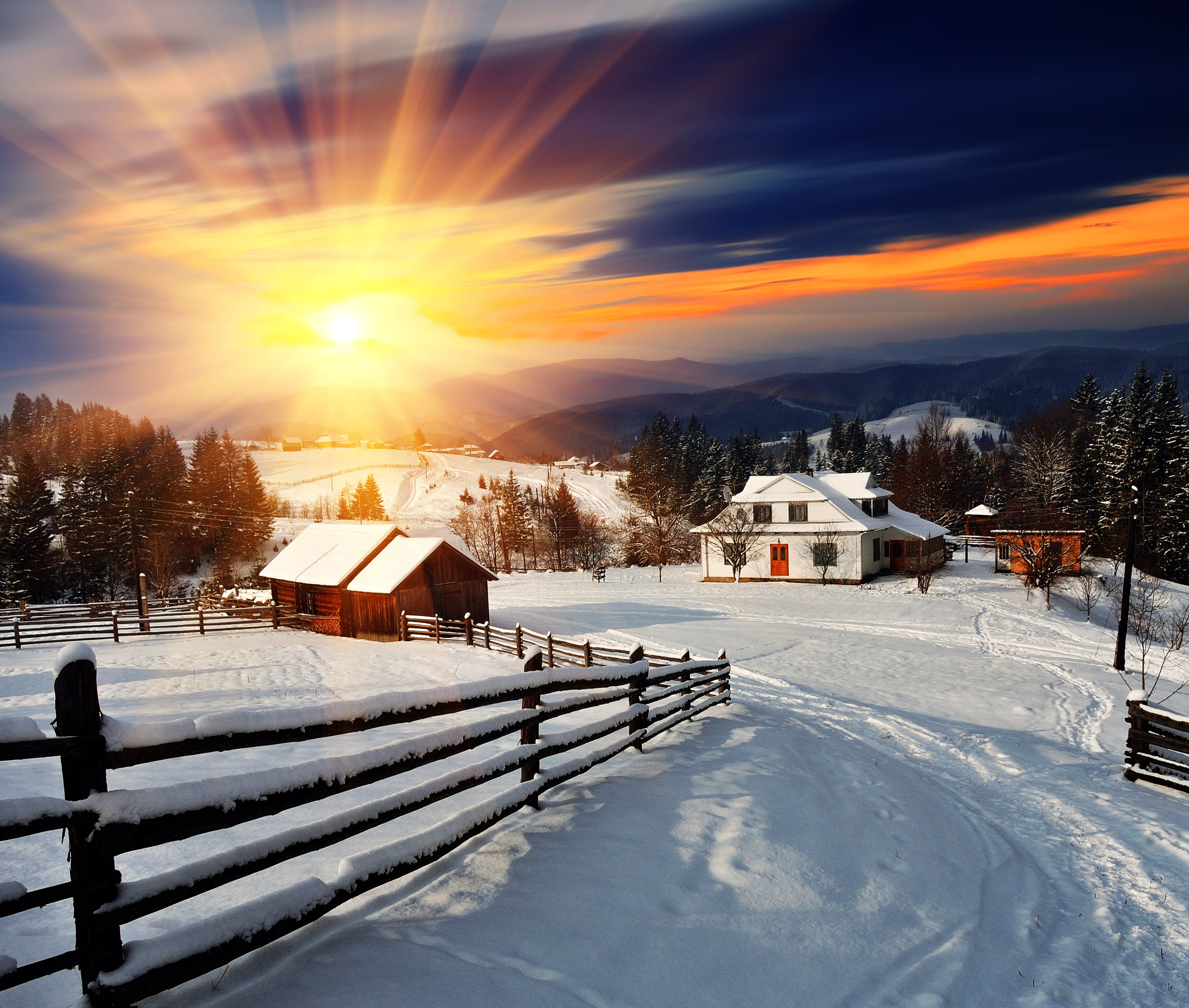 Winter village with sun rays over snow-covered landscape HD Wallpaper