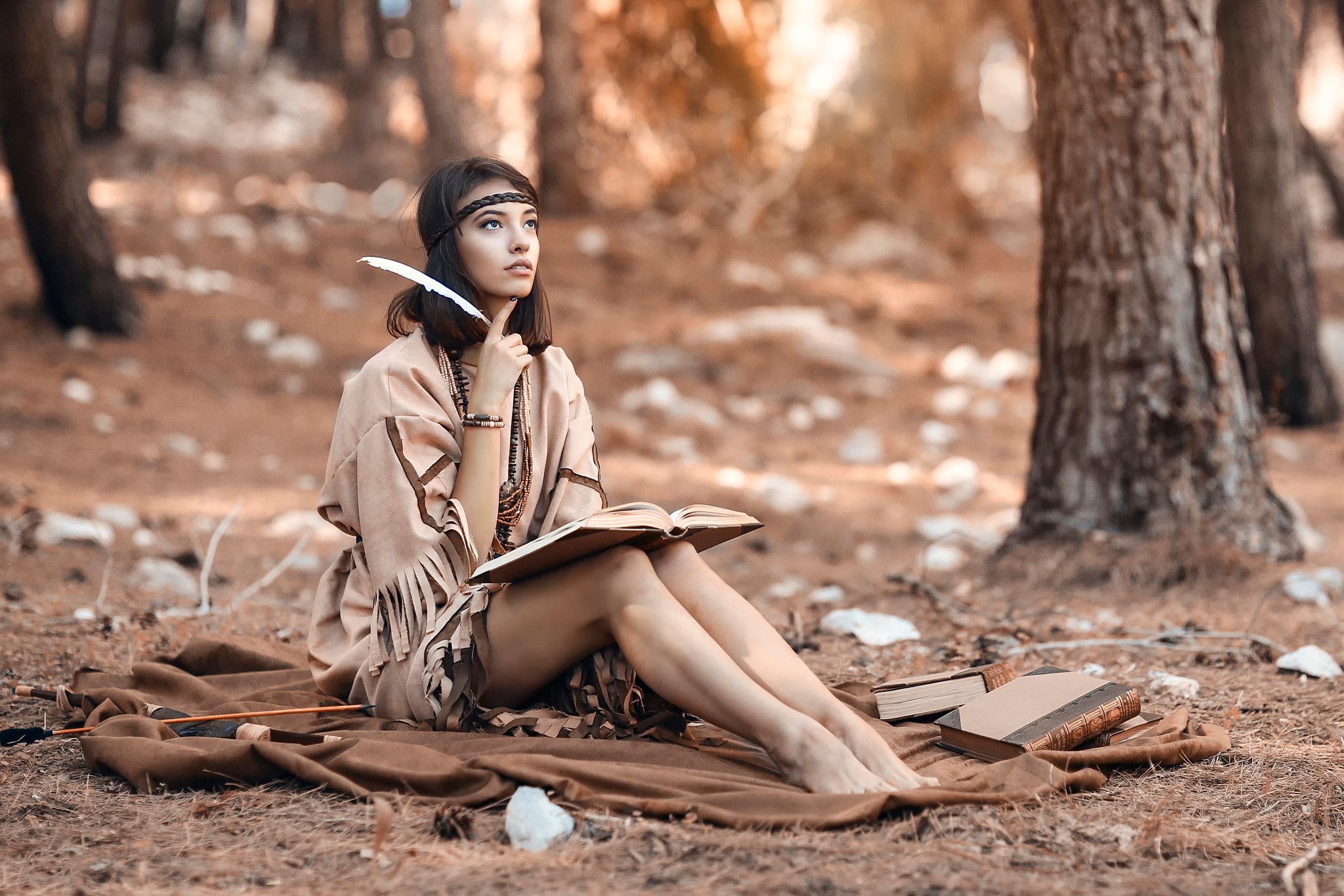 Woman in Native American attire with feather and book in woods HD Wallpaper
