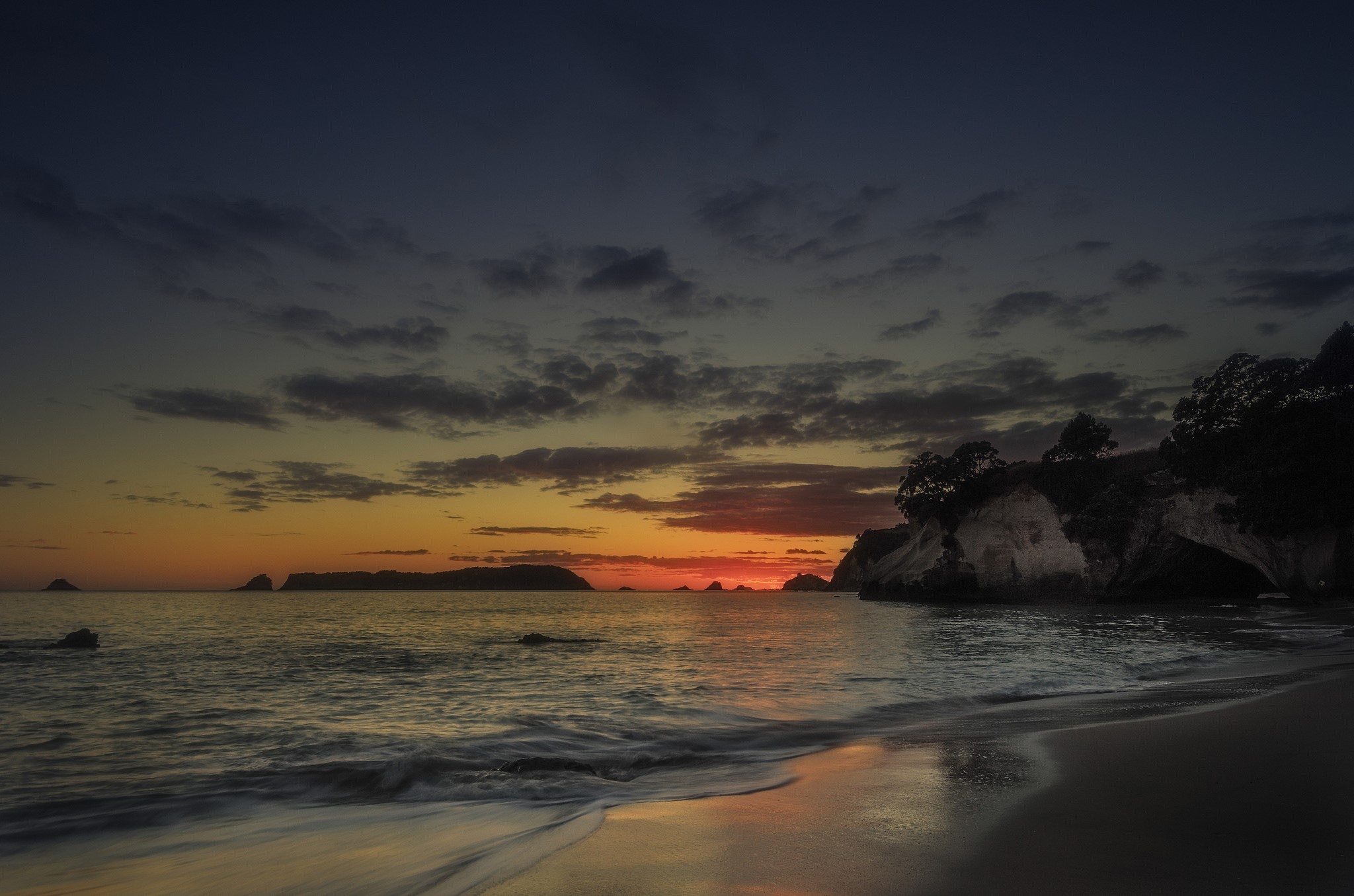 Sunset over the ocean with rocky islands and beach HD Wallpaper