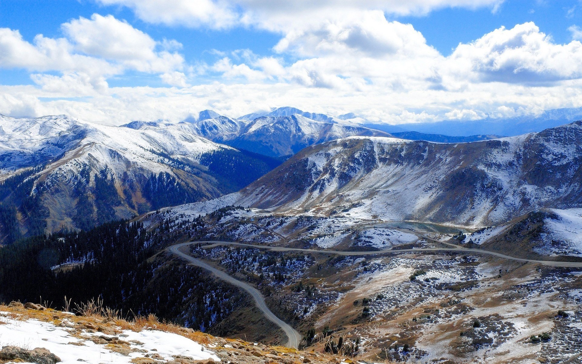 Snow-covered mountains with a winding road HD Wallpaper