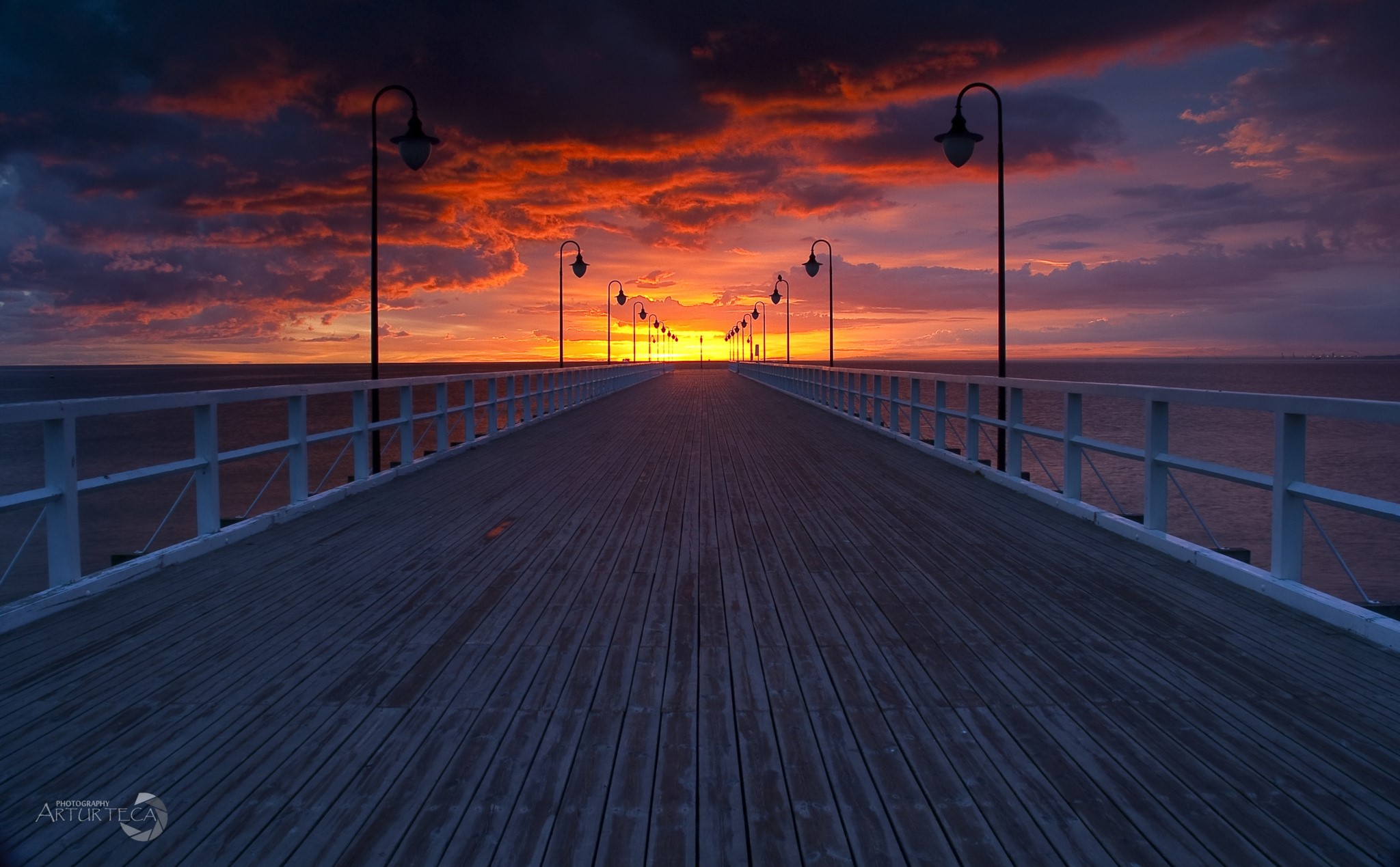 Wooden pier with streetlights at sunset over the sea HD Wallpaper