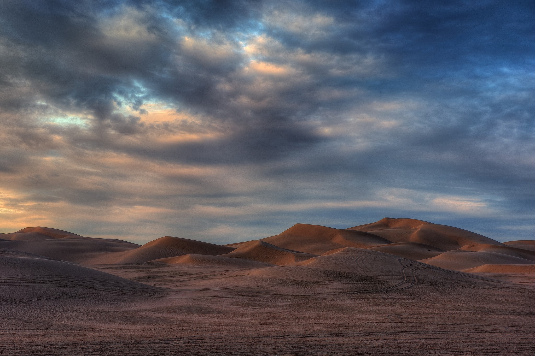 Desert dunes under a dramatic cloudy sky HD Wallpaper