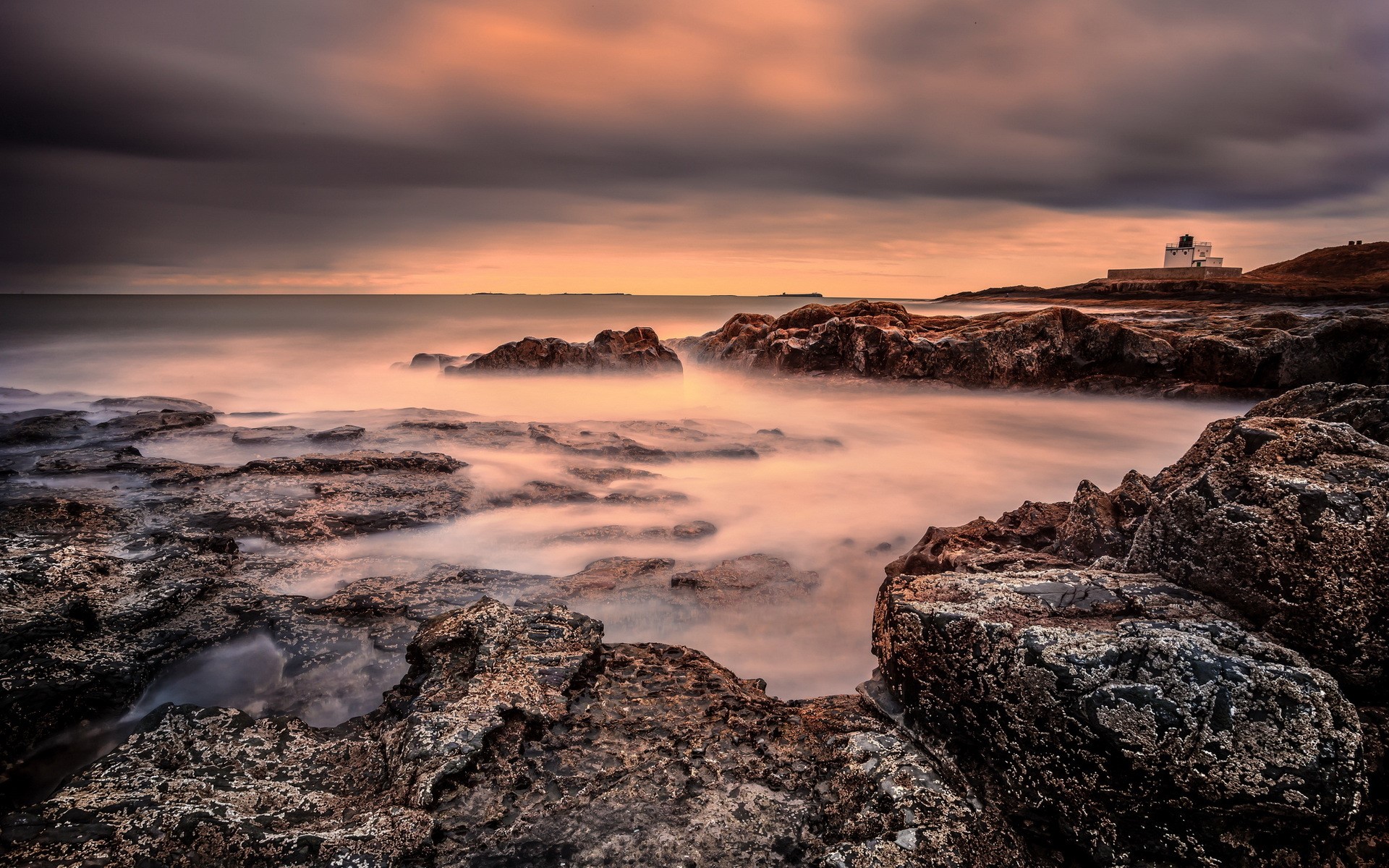 Rocky coast with lighthouse at sunset HD Wallpaper