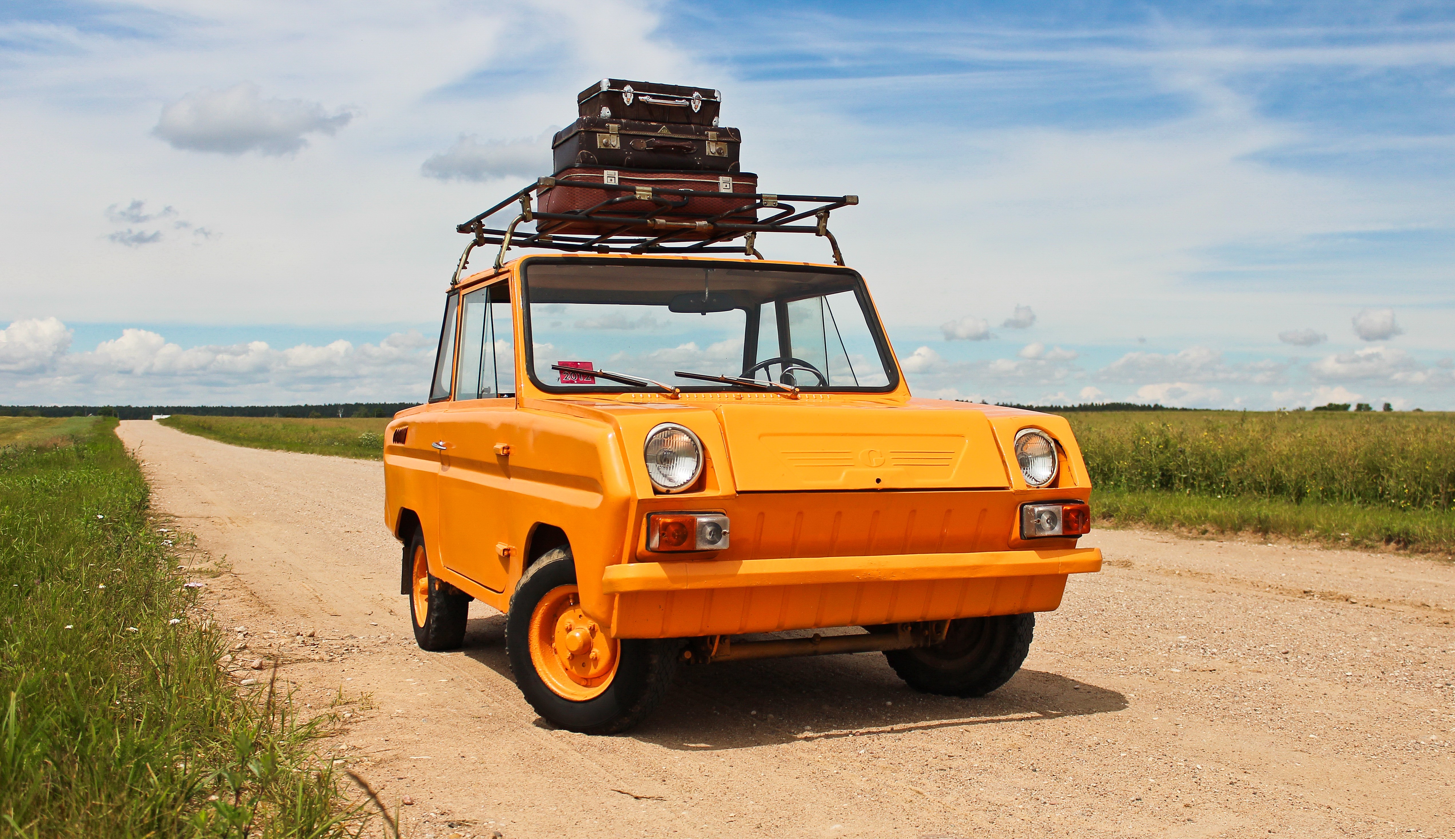 Orange SMZ cycle-car with suitcases on a dirt road HD Wallpaper