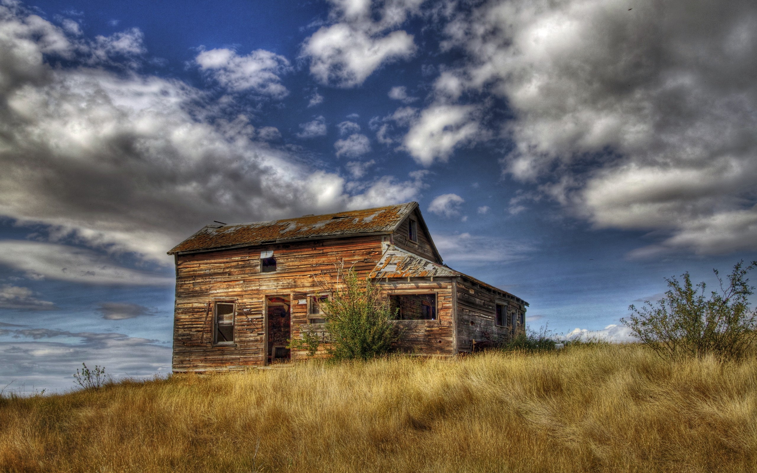Abandoned wooden house on a grassy hill under a cloudy sky HD Wallpaper