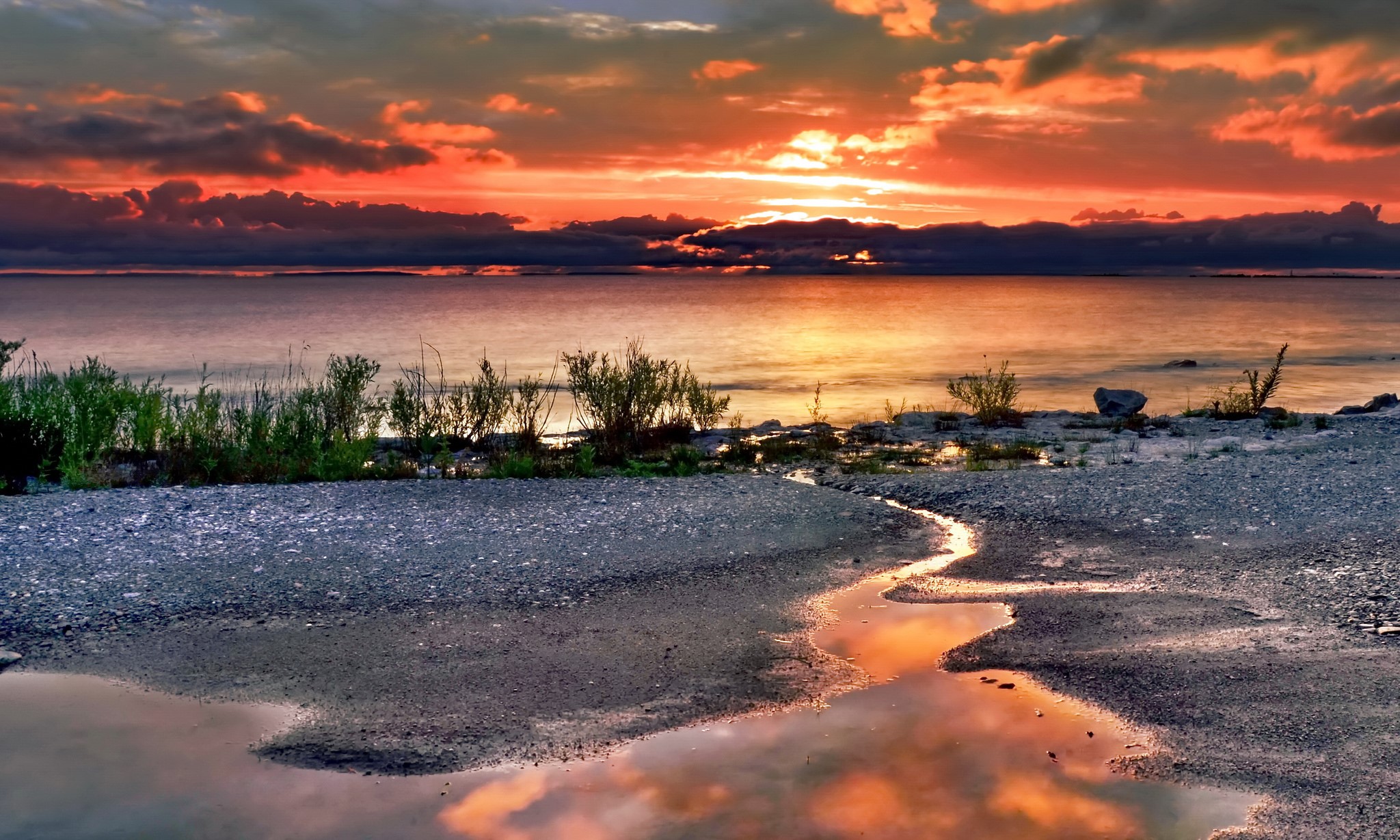 Sunset over a rocky lake shore with reflections HD Wallpaper