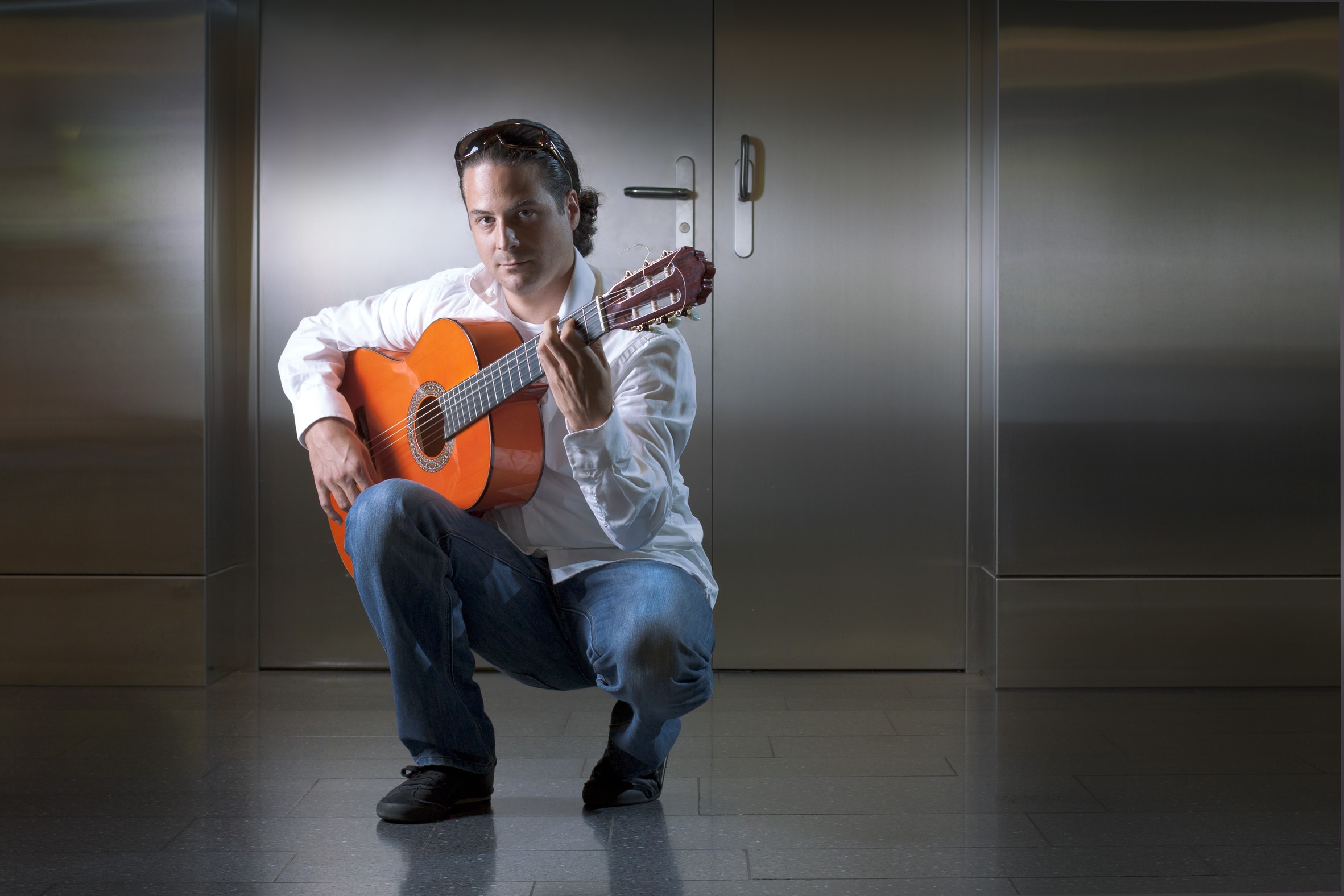 Man playing guitar in front of metal doors HD Wallpaper