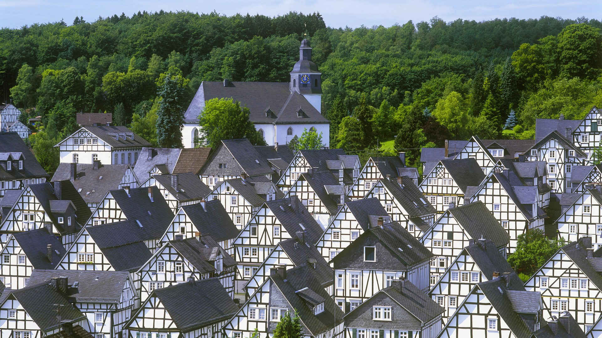 Half-timbered houses and church in a forest town HD Wallpaper