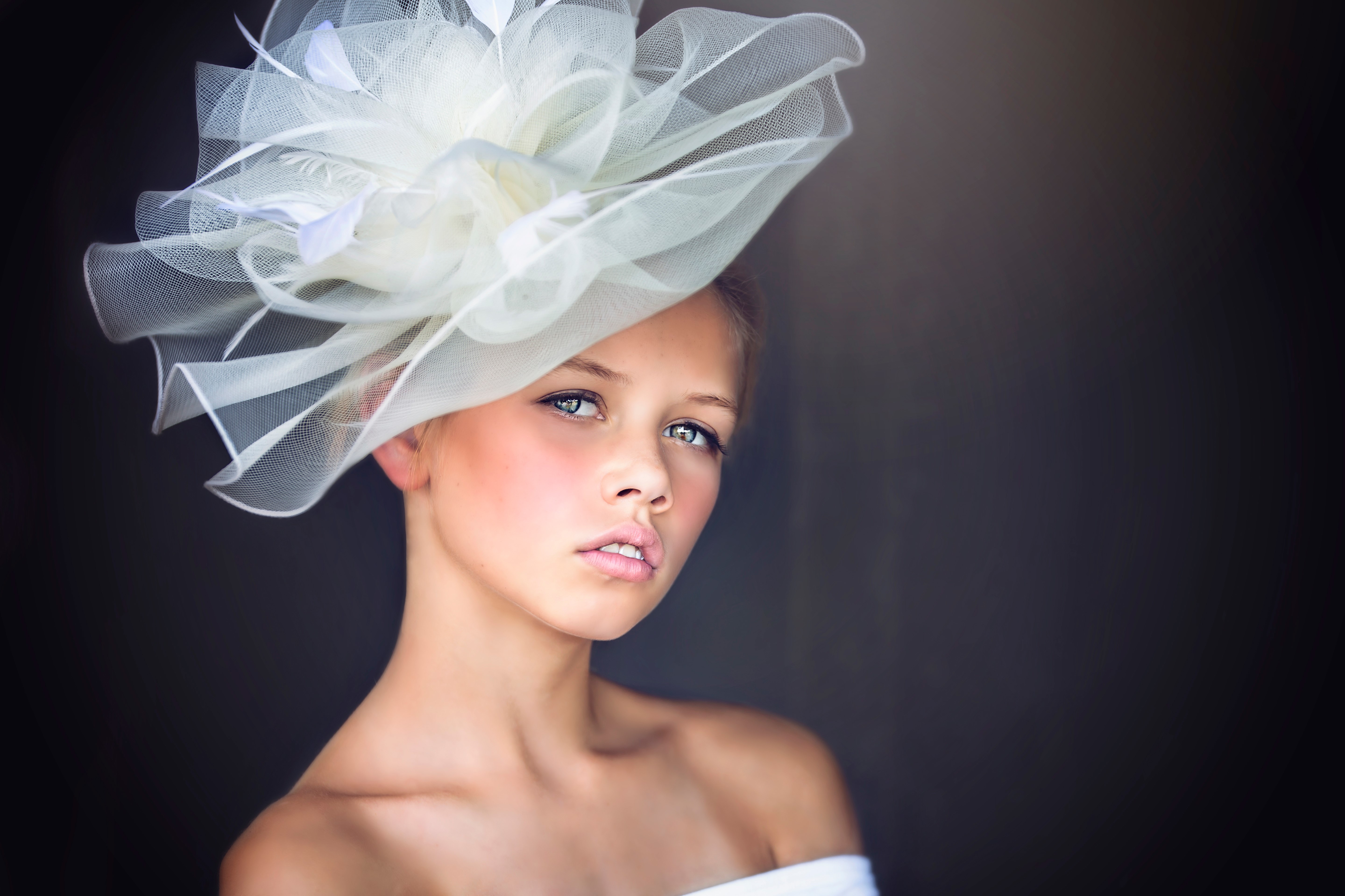 Young woman wearing a large white fascinator hat HD Wallpaper