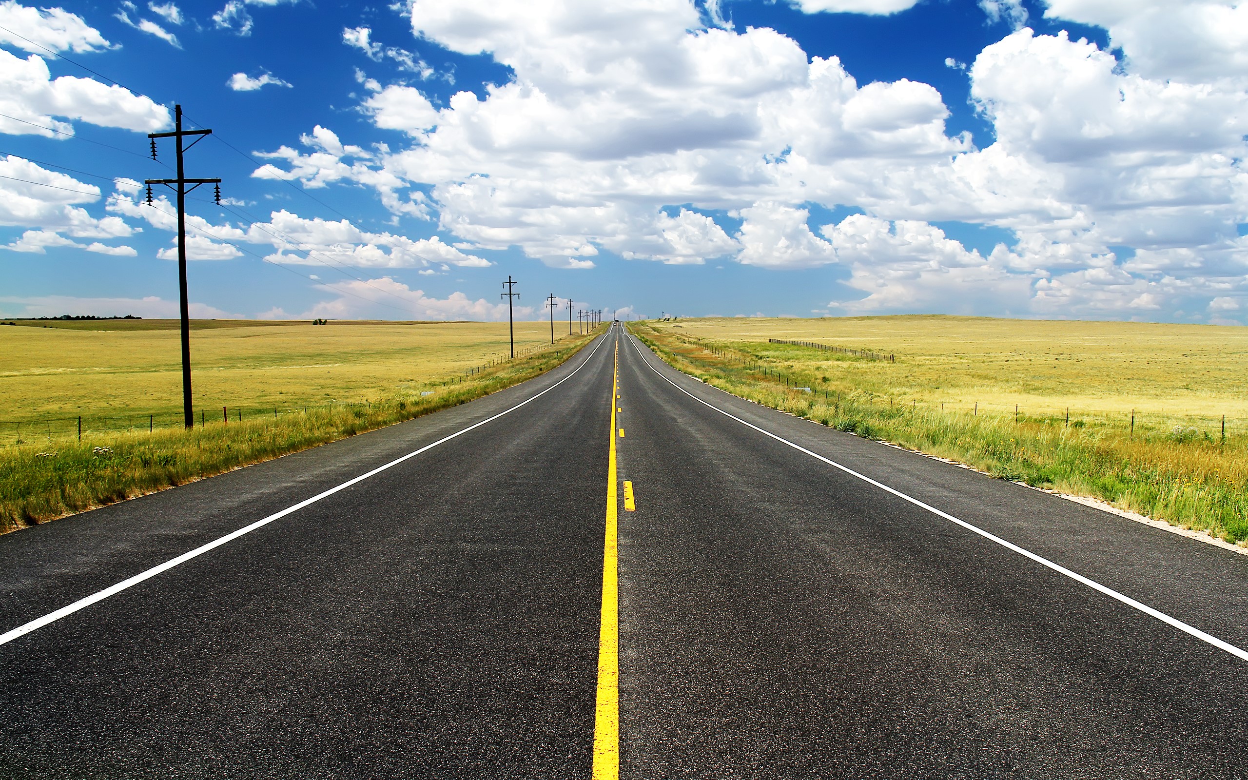 Empty highway stretching into the distance under a cloudy sky HD Wallpaper