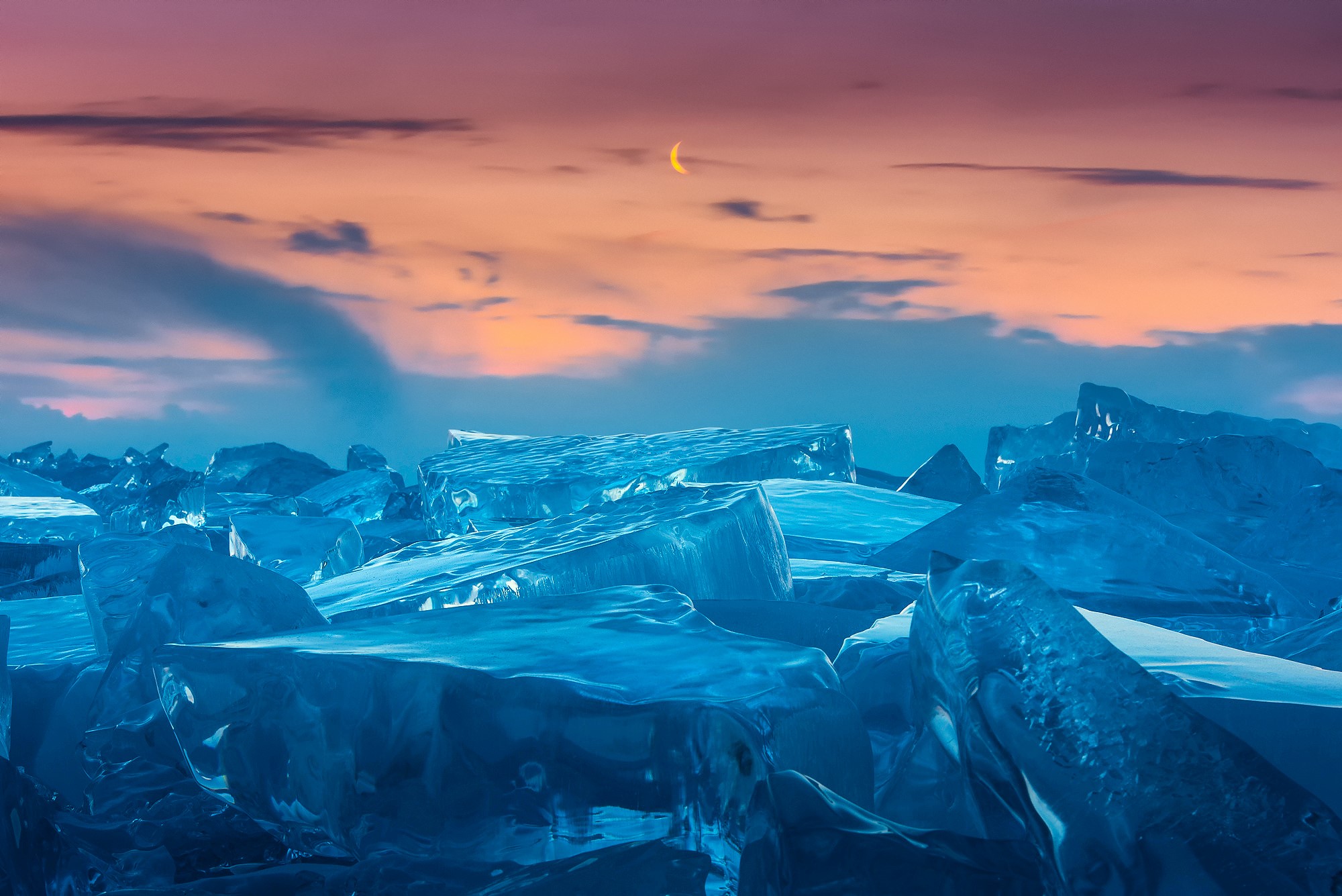 Ice formations under a crescent moon and sunset sky HD Wallpaper