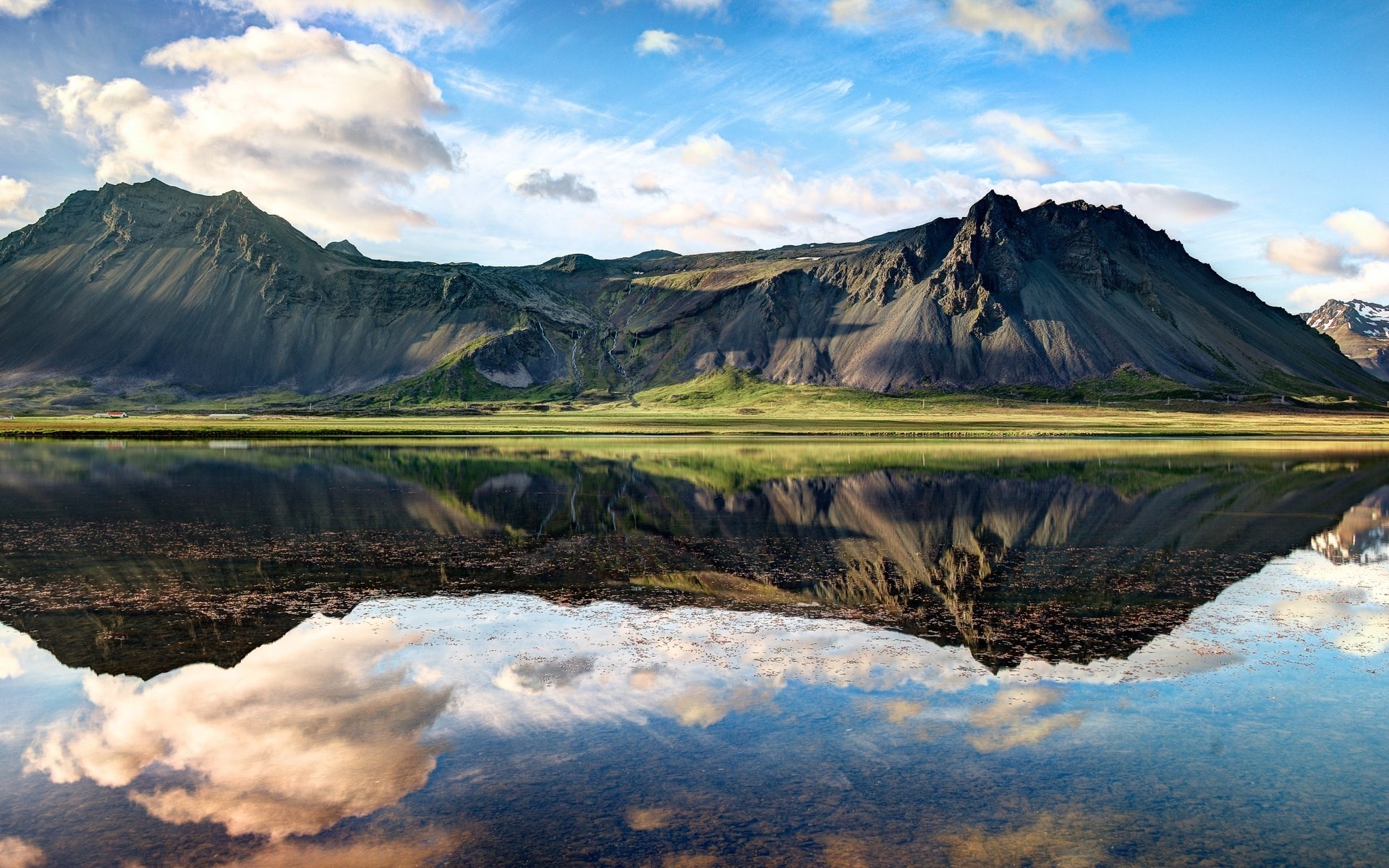 Mountain range reflected in a calm lake under a cloudy sky HD Wallpaper