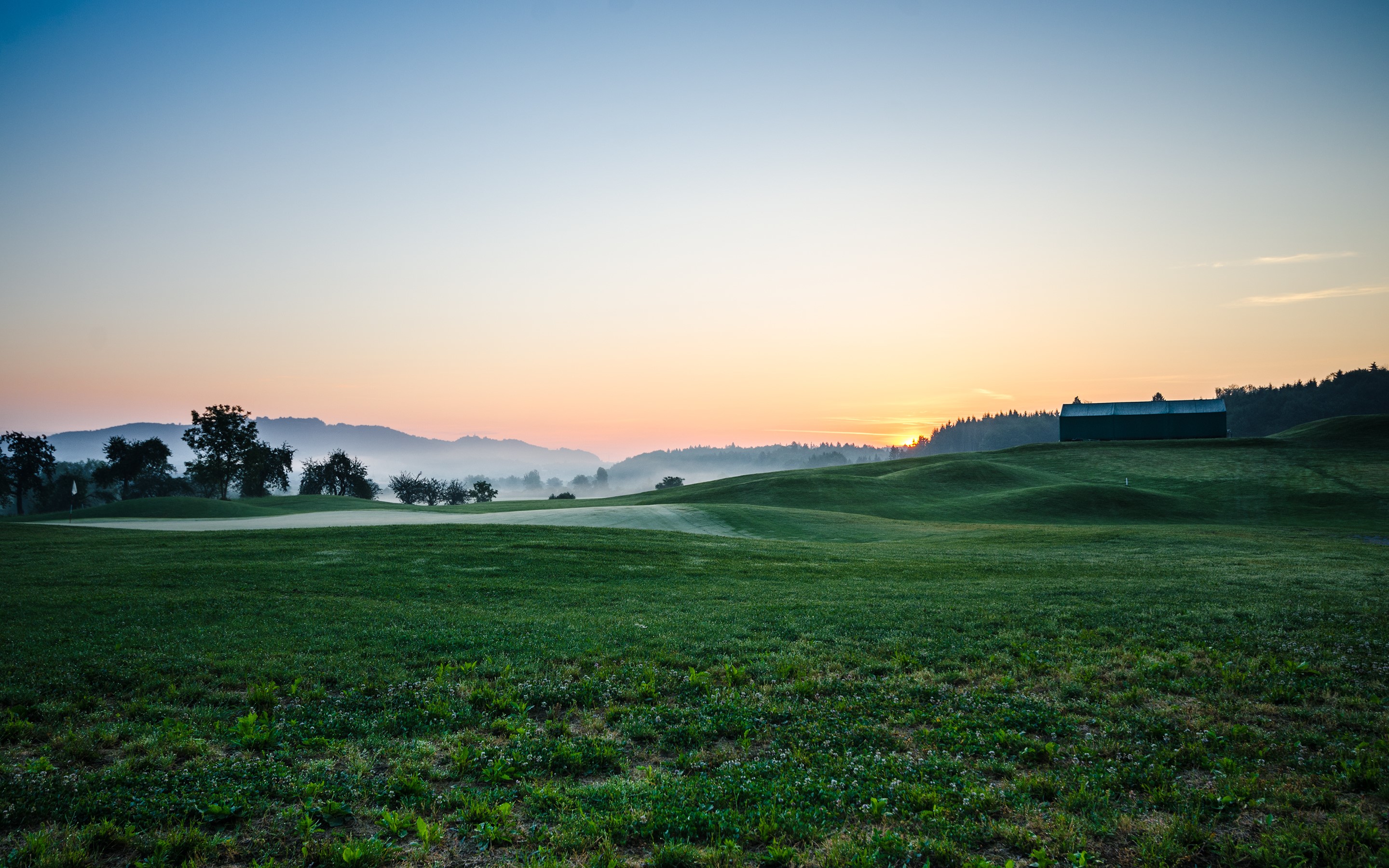 Golf course with a barn at sunrise HD Wallpaper