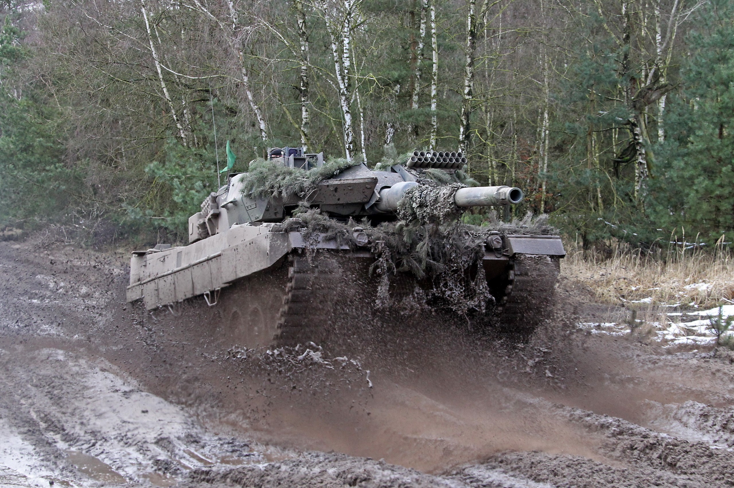 Tank driving through mud in a forest HD Wallpaper