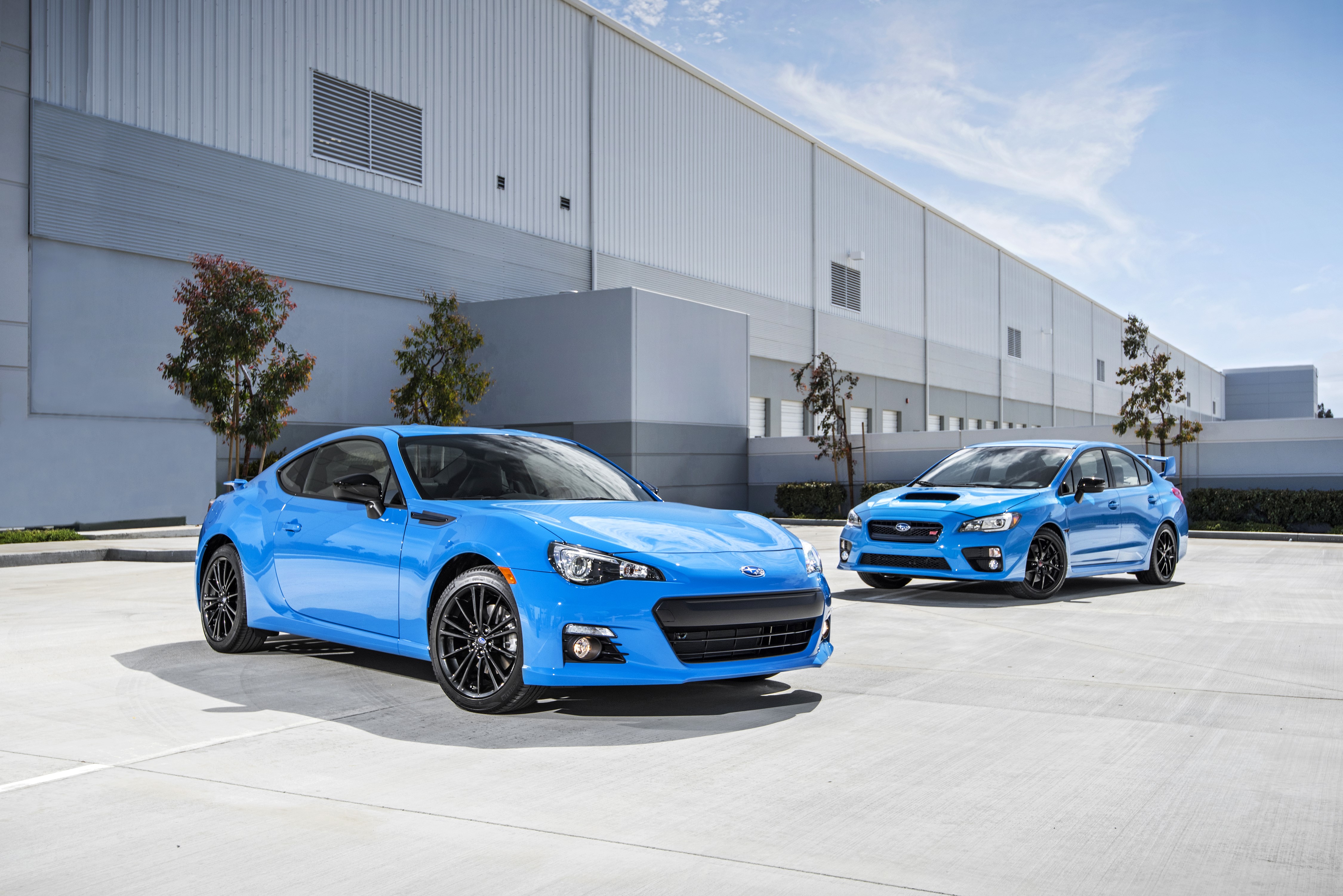 Two blue Subaru cars parked outside a building HD Wallpaper