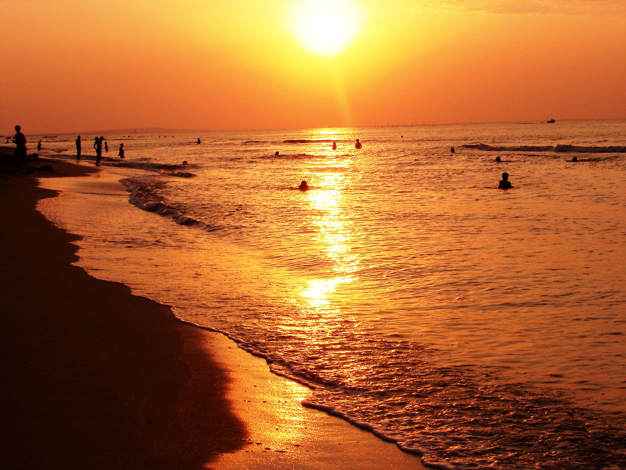Sunset over the sea with people swimming HD Wallpaper