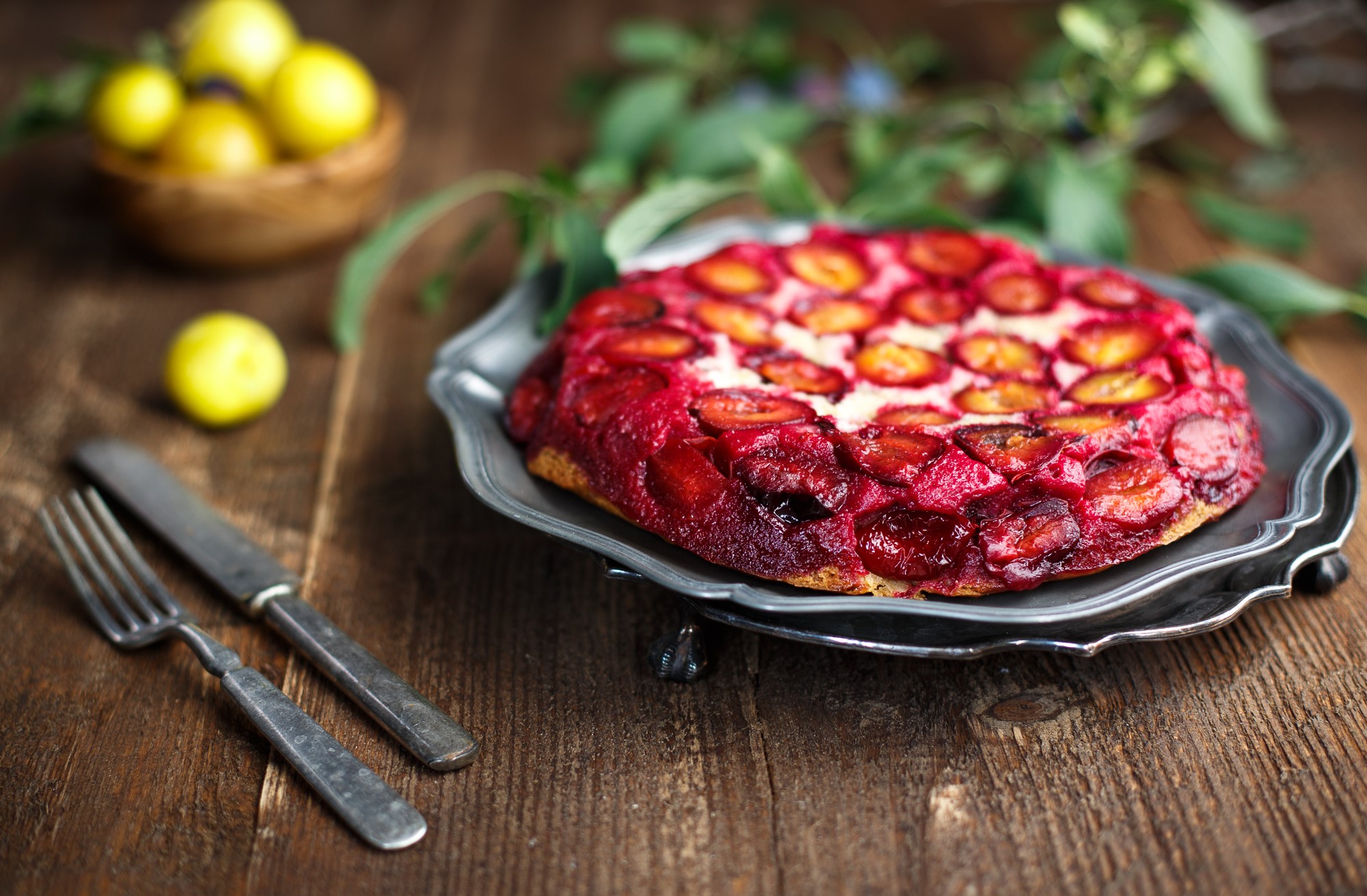 Plum upside-down cake on a platter with fork and knife HD Wallpaper
