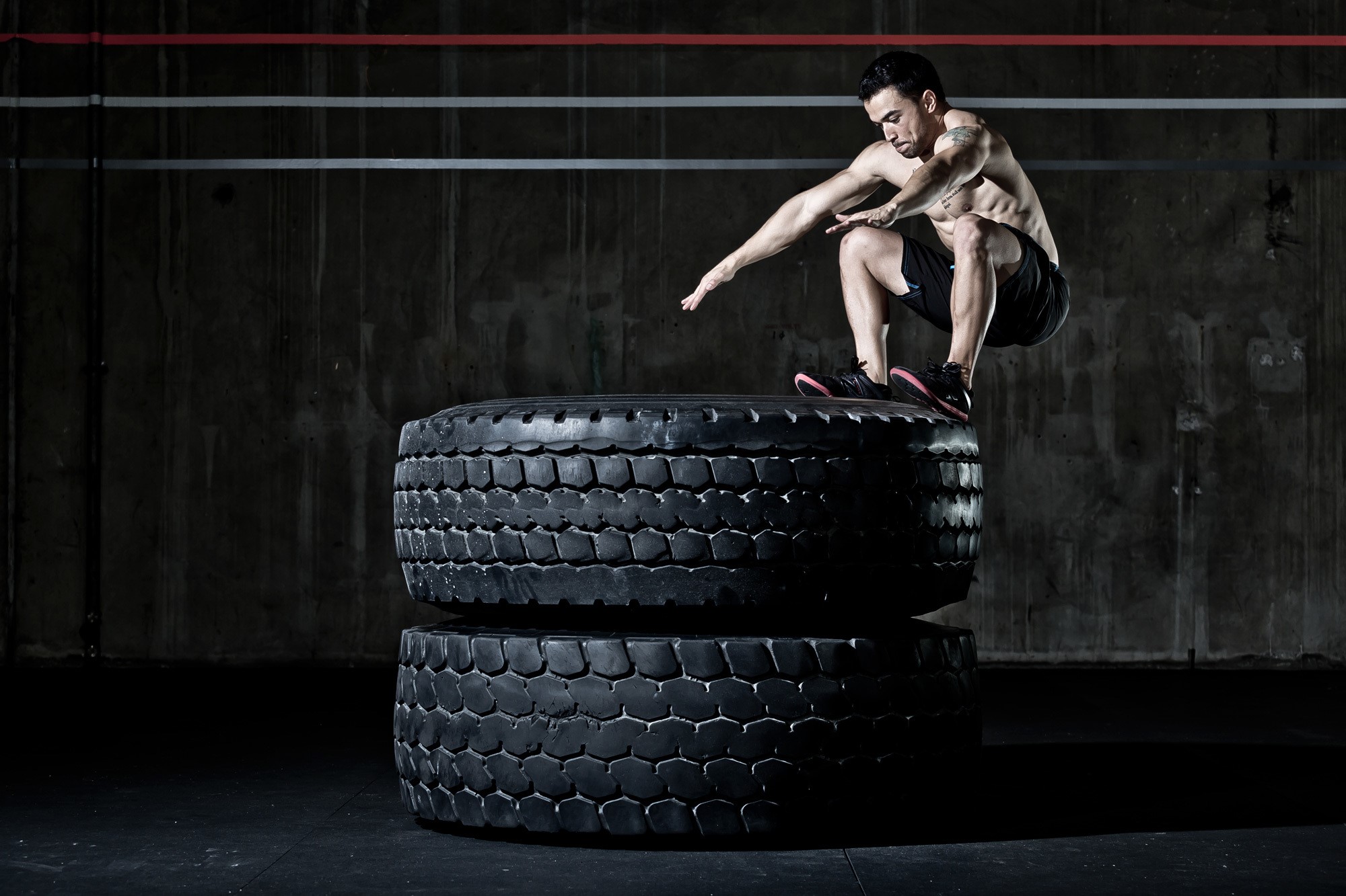 Man performing a tire jump workout HD Wallpaper