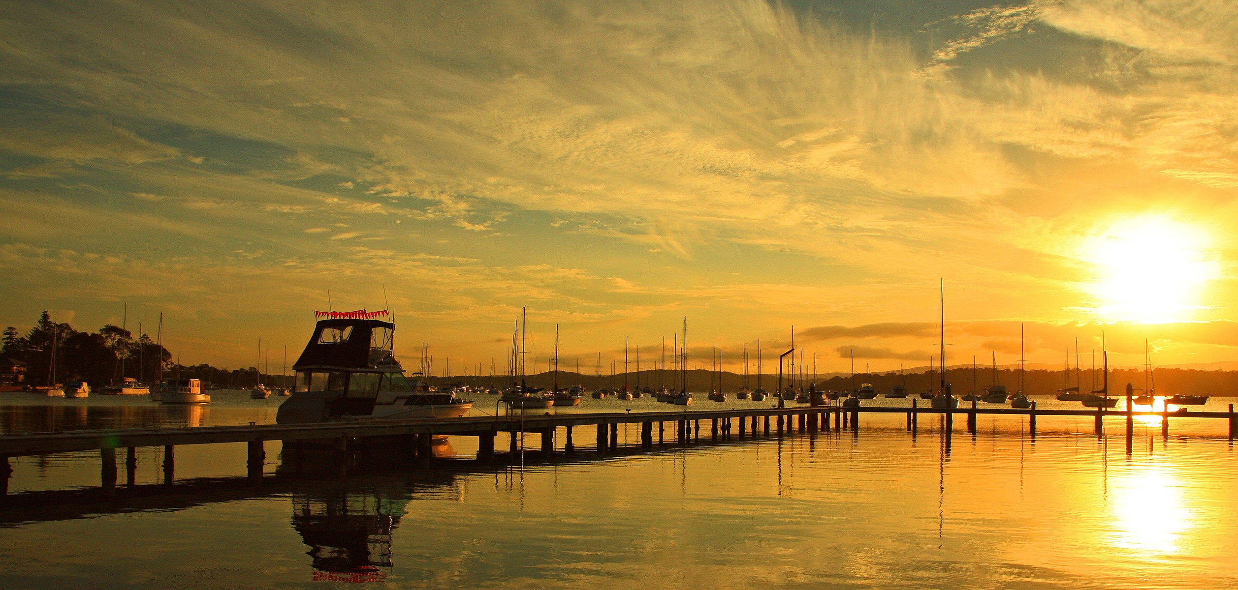 Boats docked at a pier during a golden sunset HD Wallpaper
