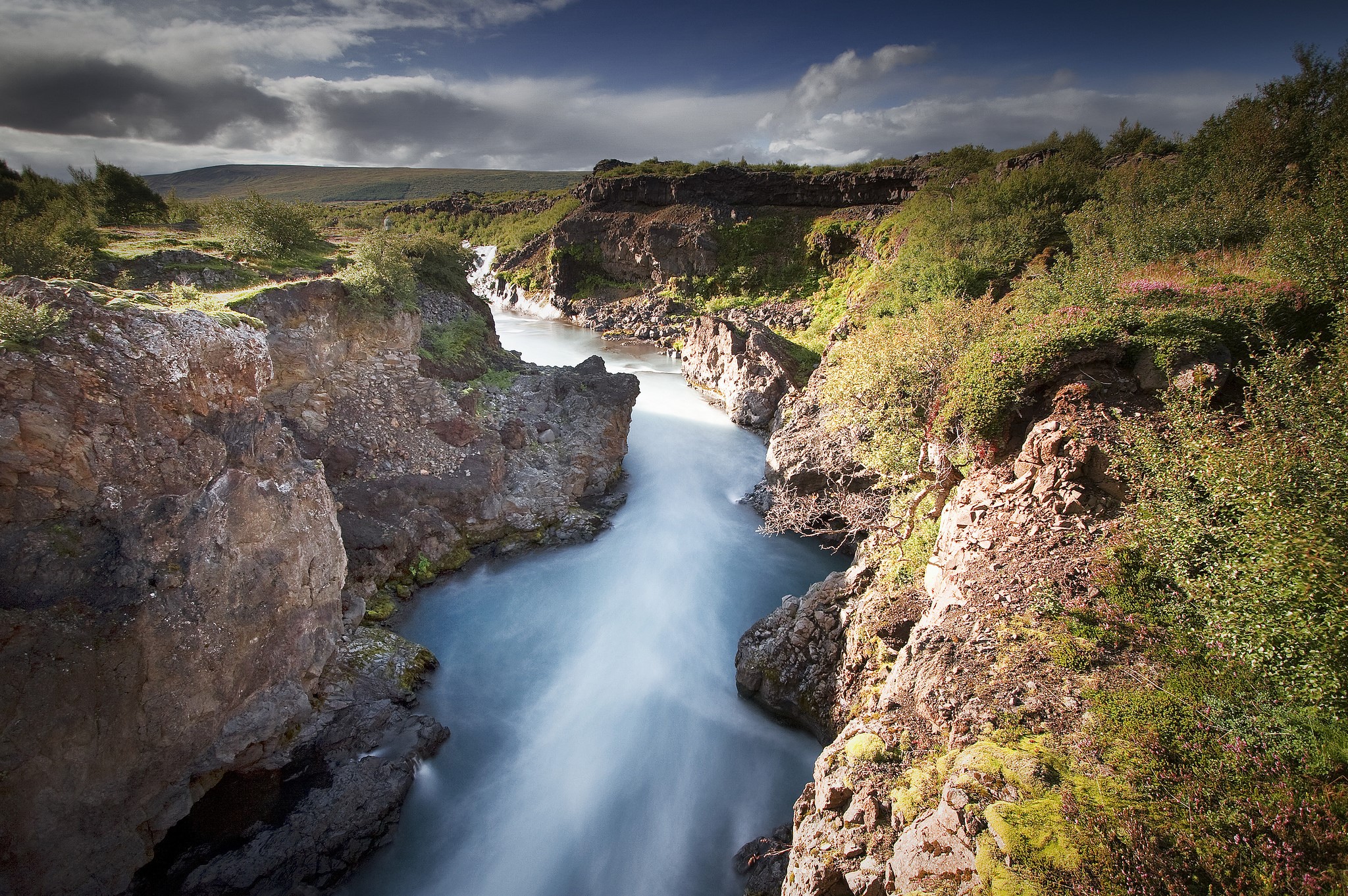 River flowing through a rocky gorge with vegetation HD Wallpaper