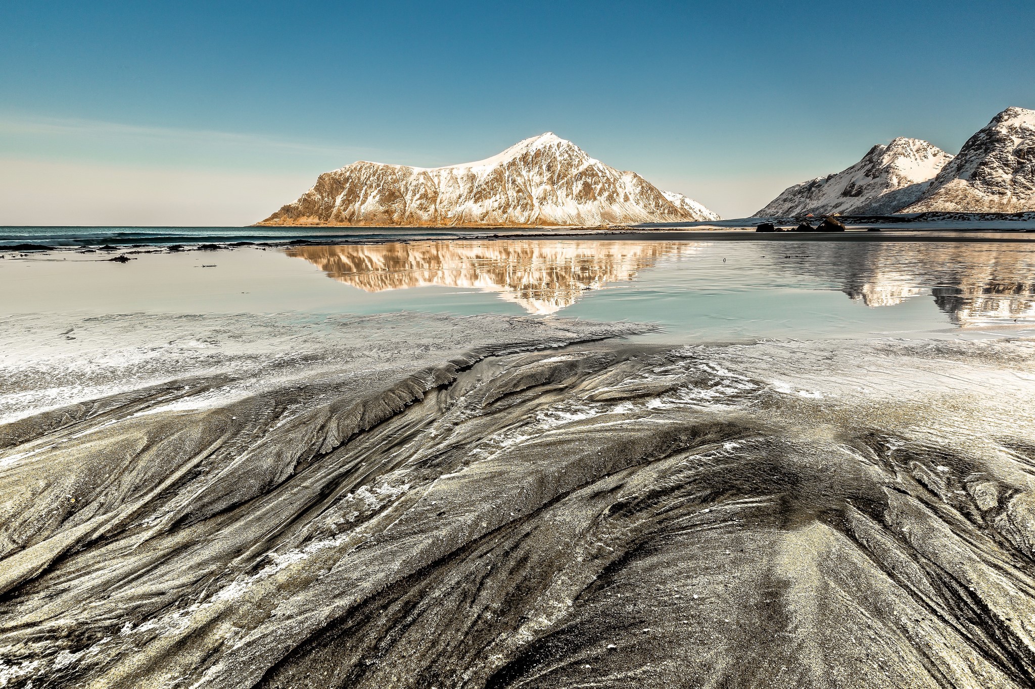 Snow-capped mountains reflected in the sea at a beach HD Wallpaper