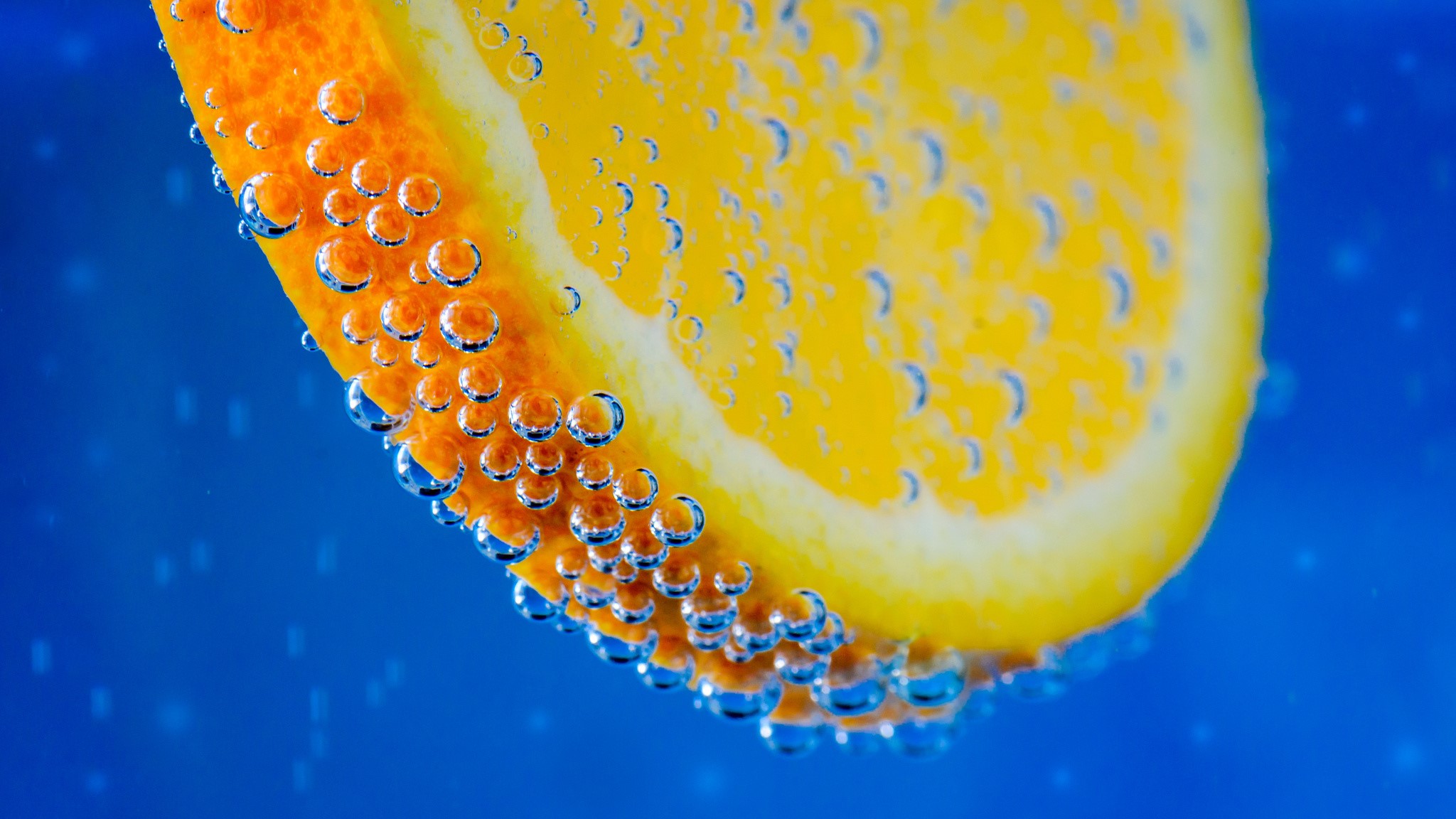 Orange slice with bubbles in blue liquid HD Wallpaper