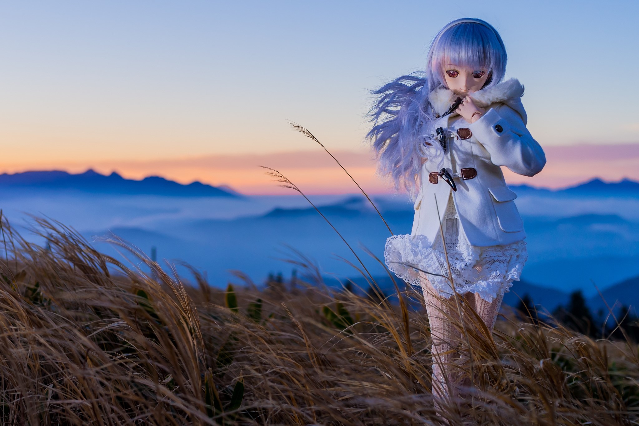 Doll in a white coat on a mountain at sunset HD Wallpaper