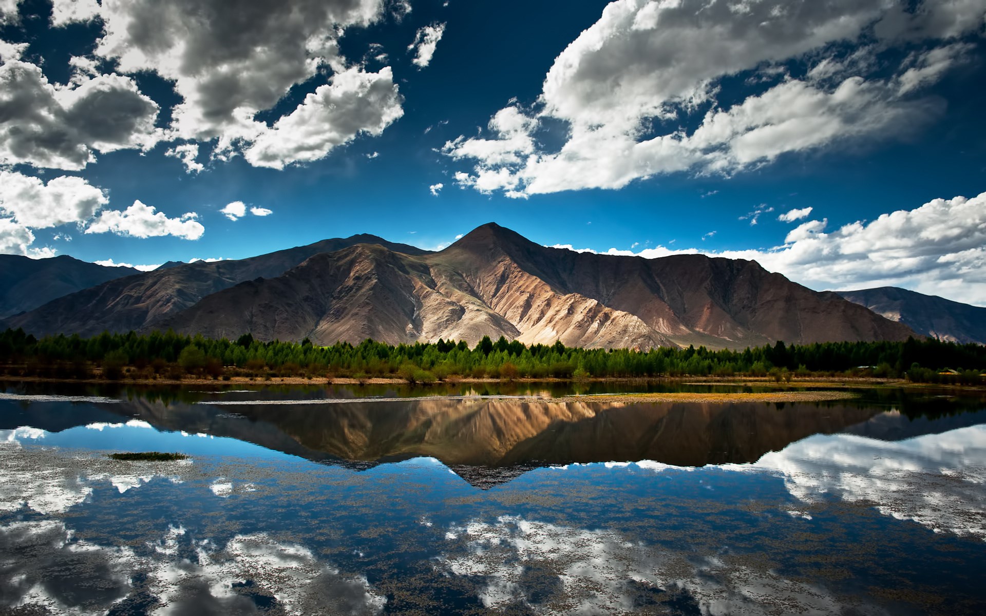 Mountain range reflected in a calm lake under a cloudy sky HD Wallpaper