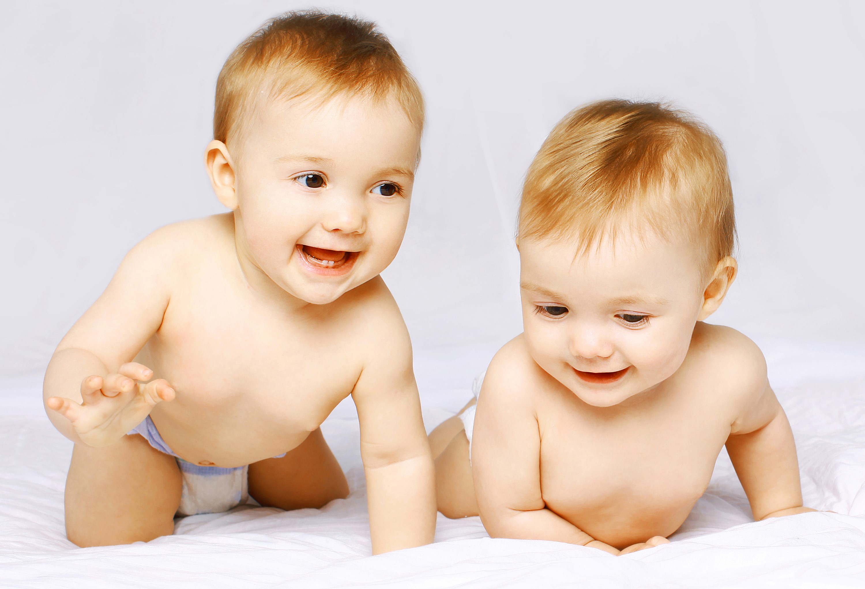 Two babies crawling on a white surface HD Wallpaper