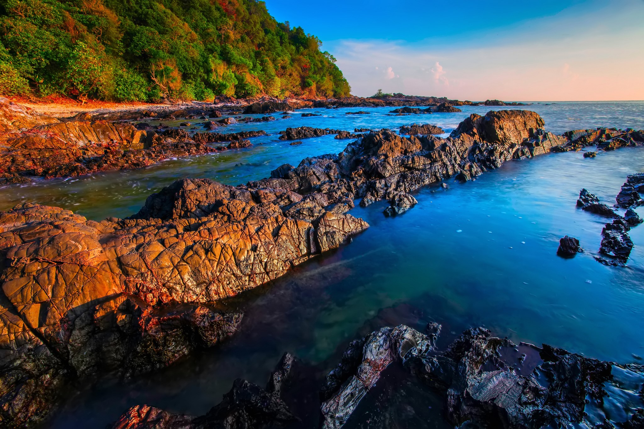 Rocky coast with green trees and blue sea HD Wallpaper