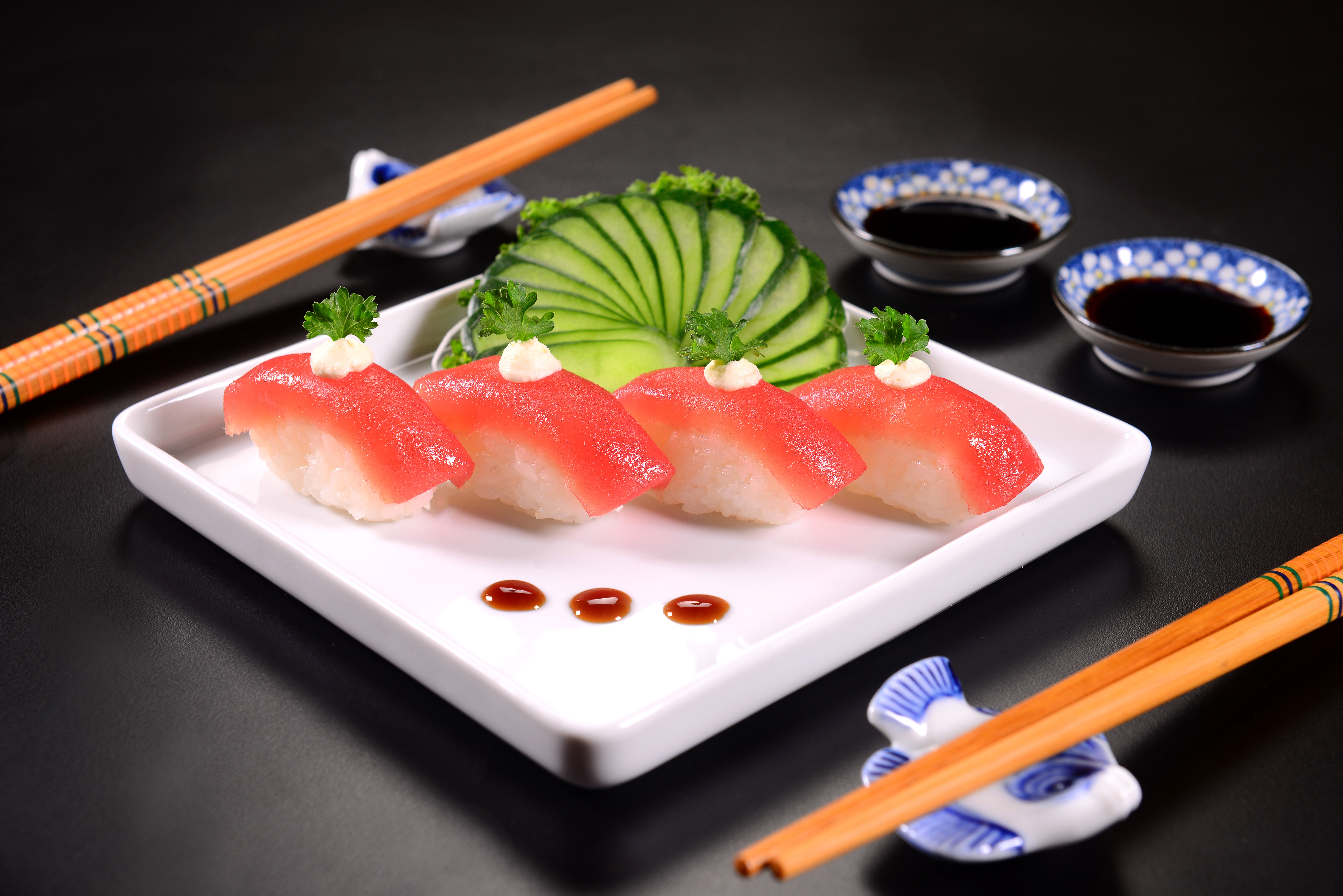 Four pieces of tuna sushi with cucumber garnish HD Wallpaper