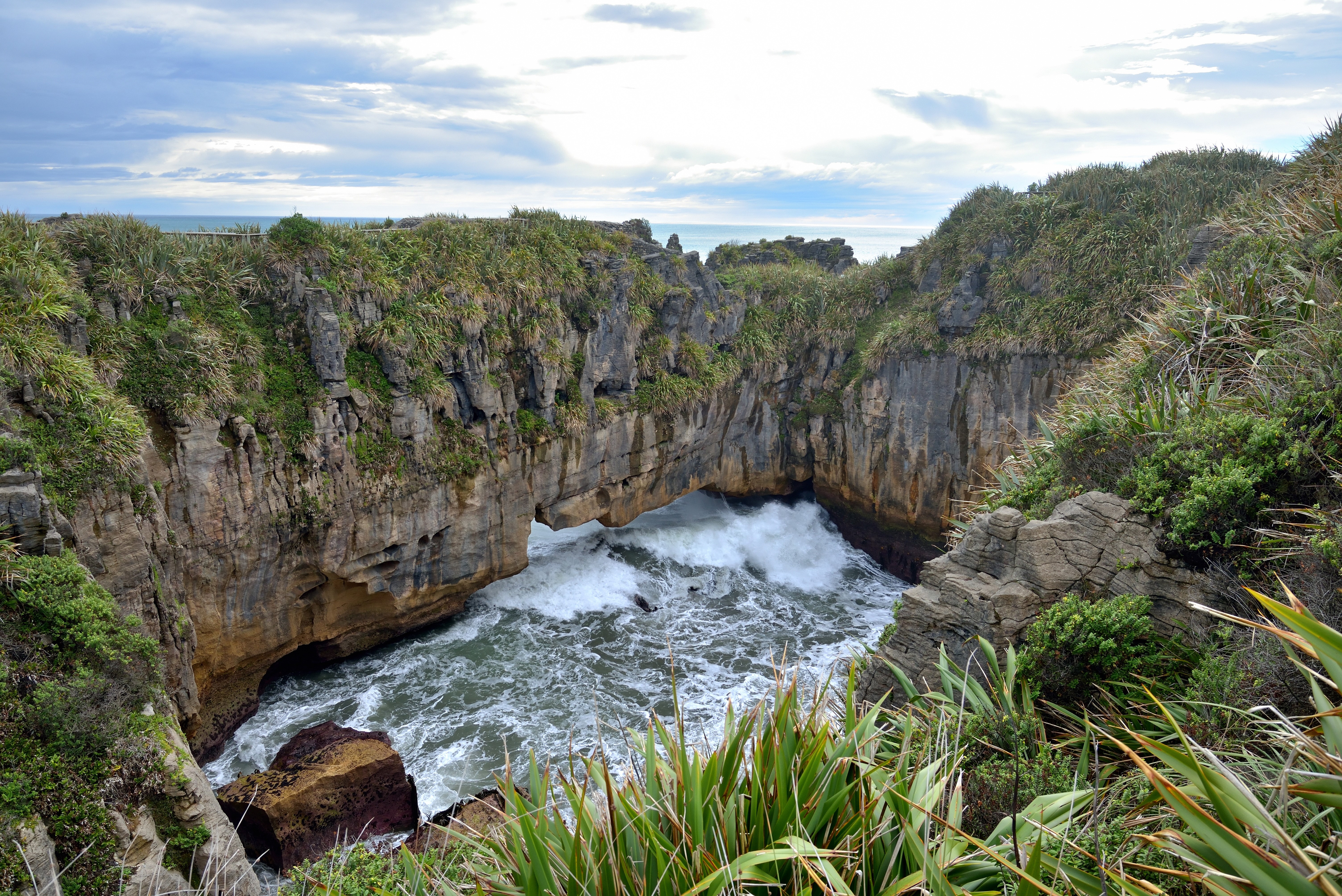 Waves crashing through rock archway at Punakaiki HD Wallpaper