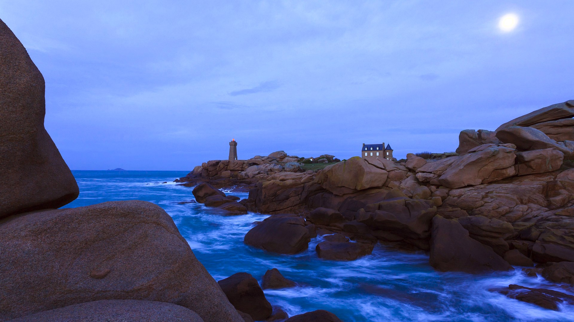 Lighthouse and house on rocky coast at dusk HD Wallpaper