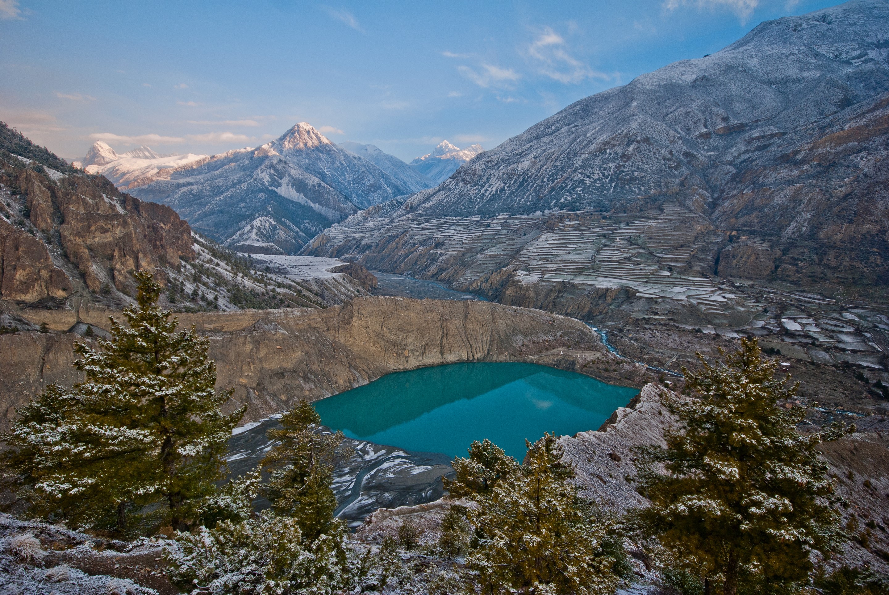 Turquoise lake in a snowy mountain valley with terraced fields HD Wallpaper