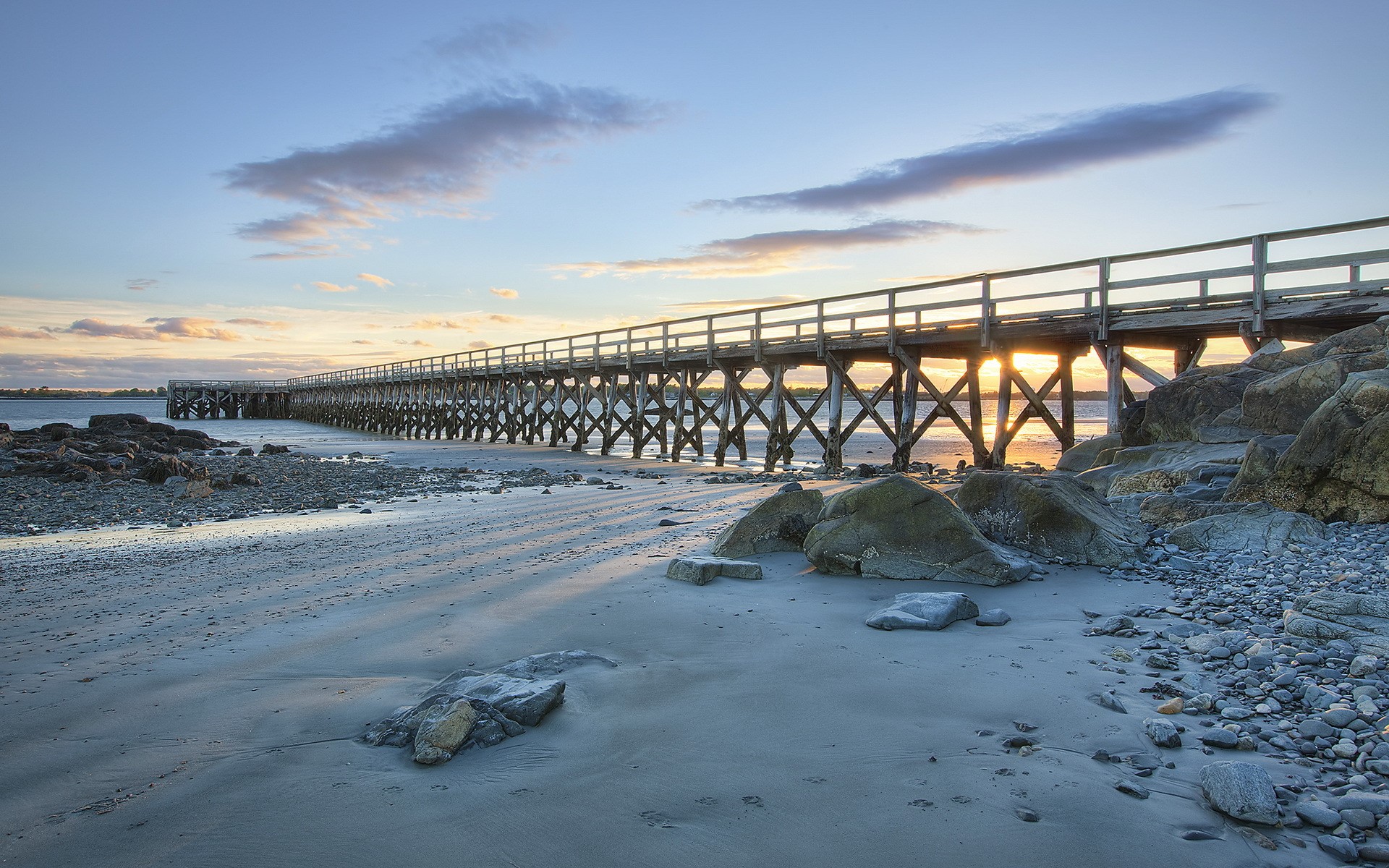 Wooden pier over a rocky beach at sunset HD Wallpaper