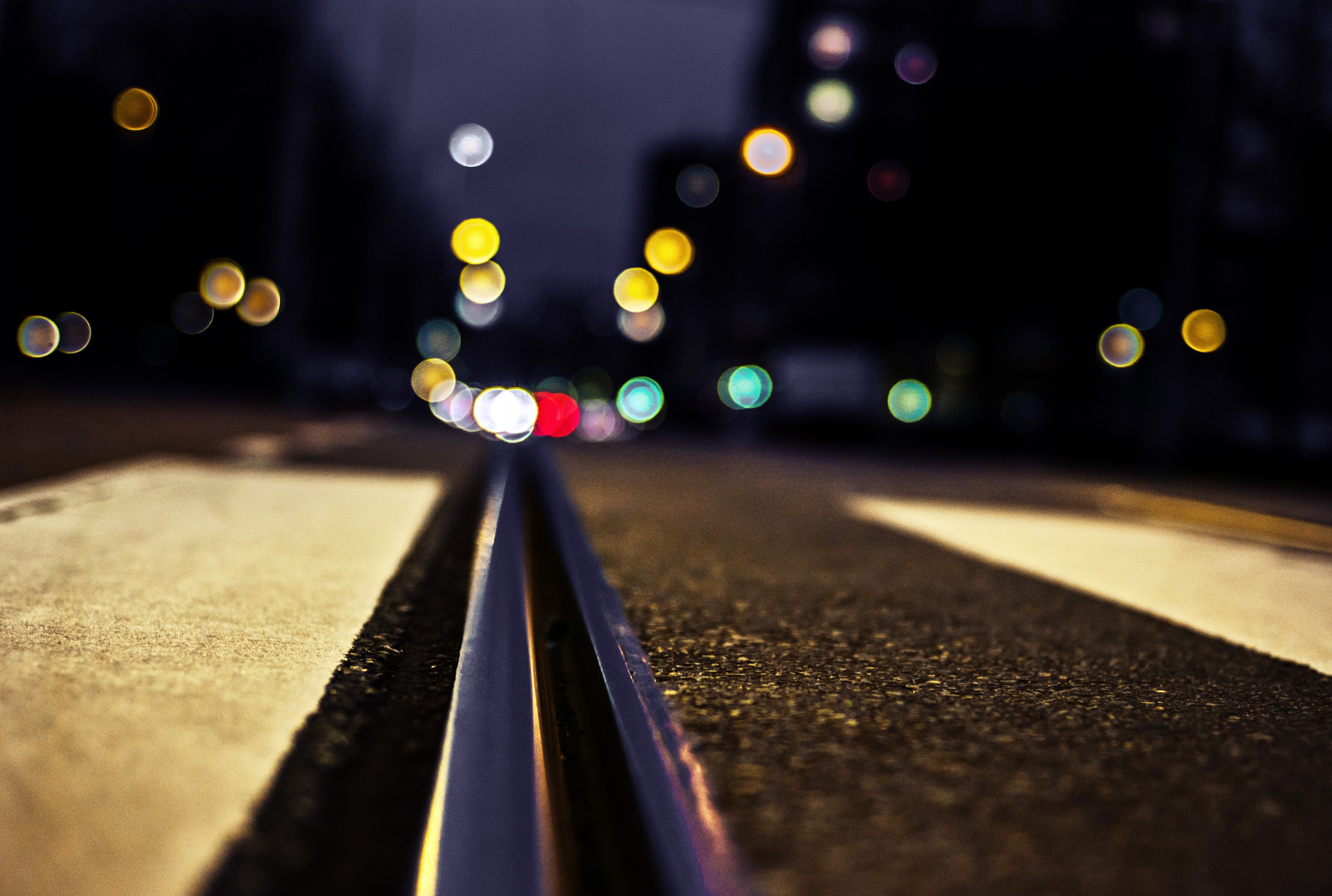 Close-up of railroad tracks at night with bokeh lights HD Wallpaper