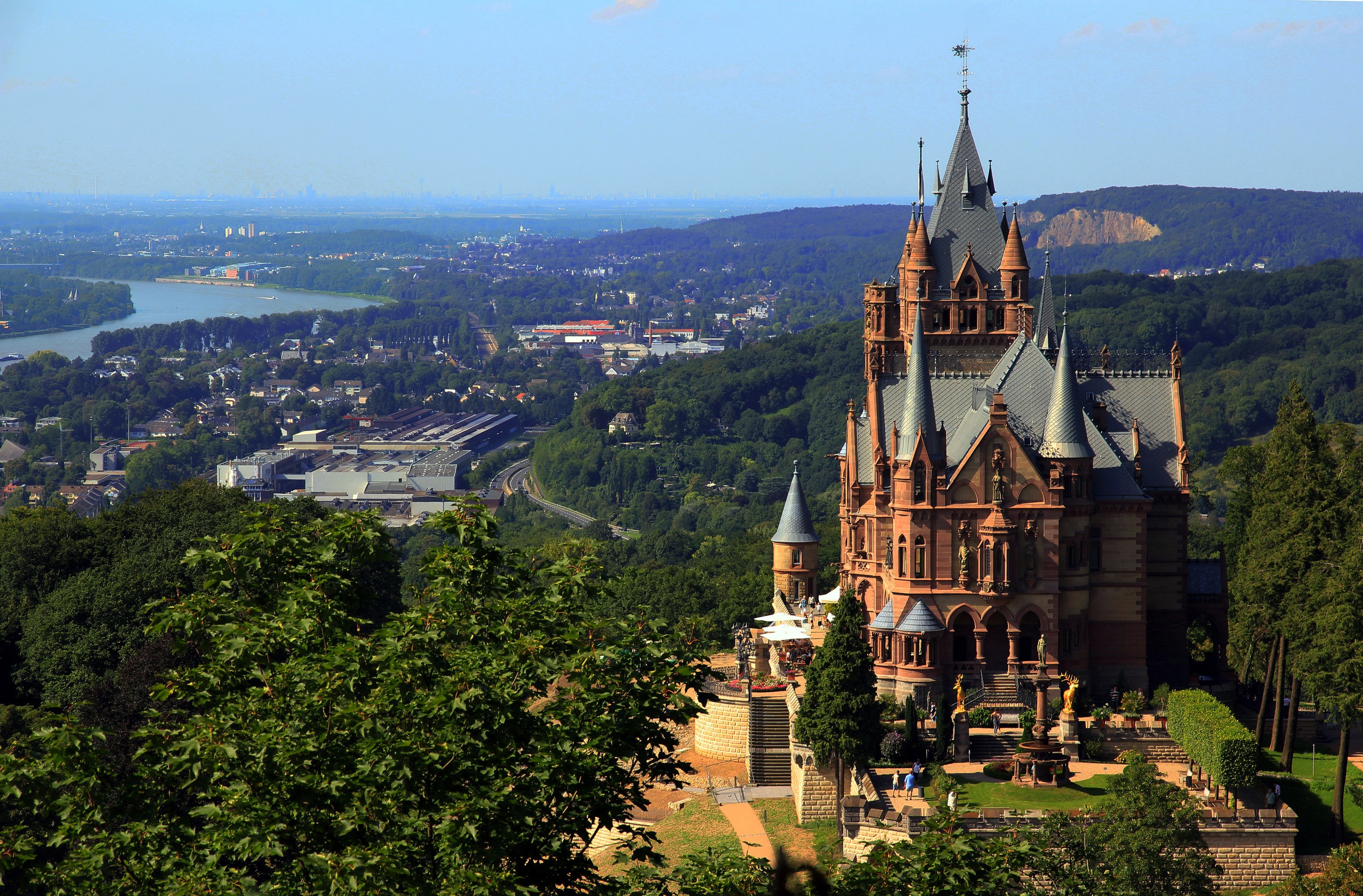 Schloss Drachenburg castle overlooking a river and town in Germany HD Wallpaper