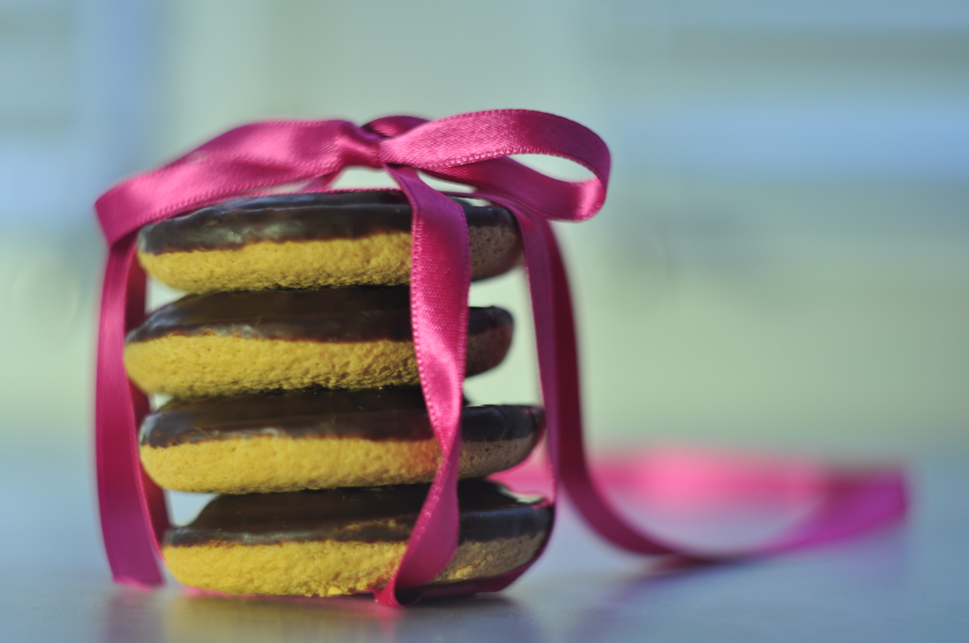 Stack of chocolate-covered cookies tied with a pink ribbon HD Wallpaper