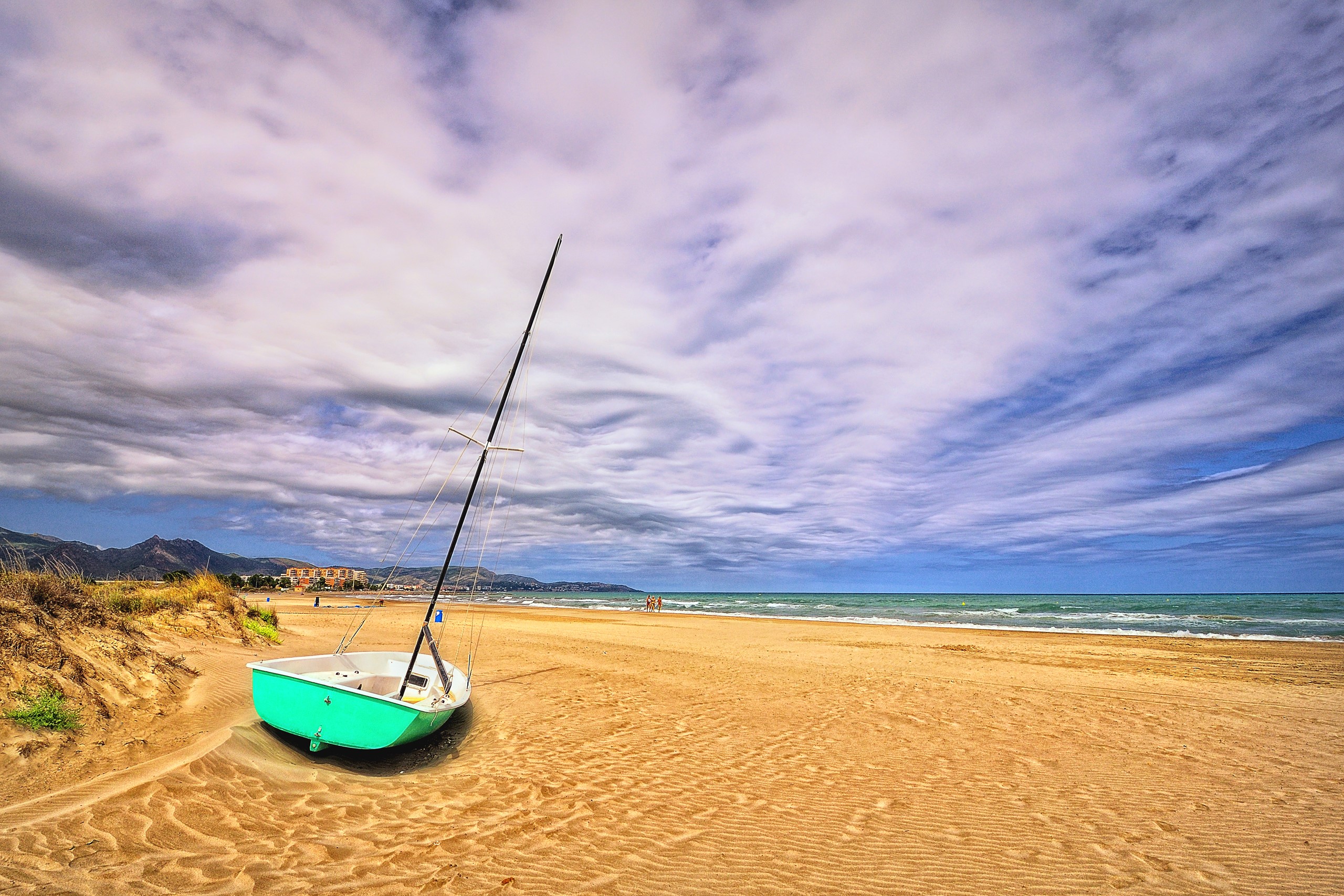 Sailboat on a sandy beach with cloudy sky HD Wallpaper