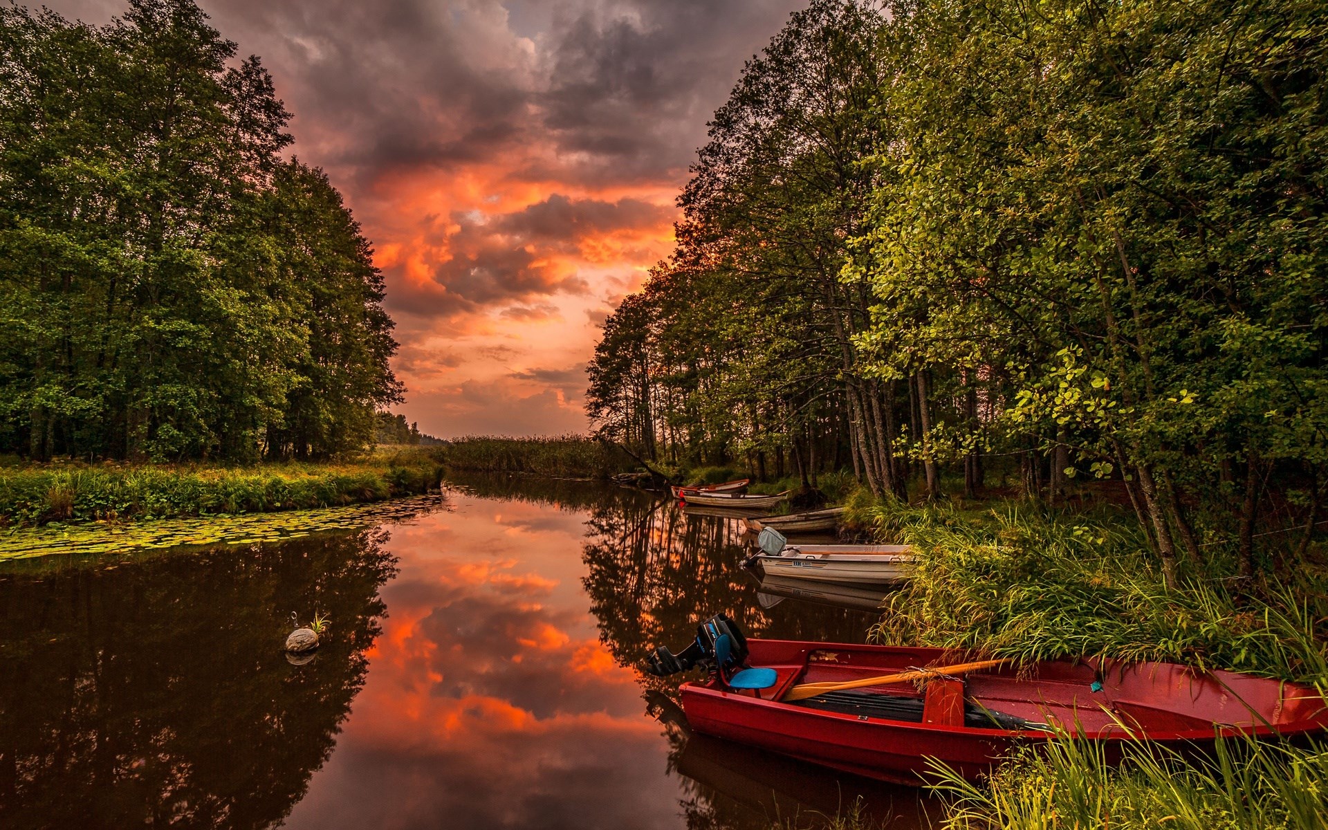 Boats on a river during a fiery sunset HD Wallpaper