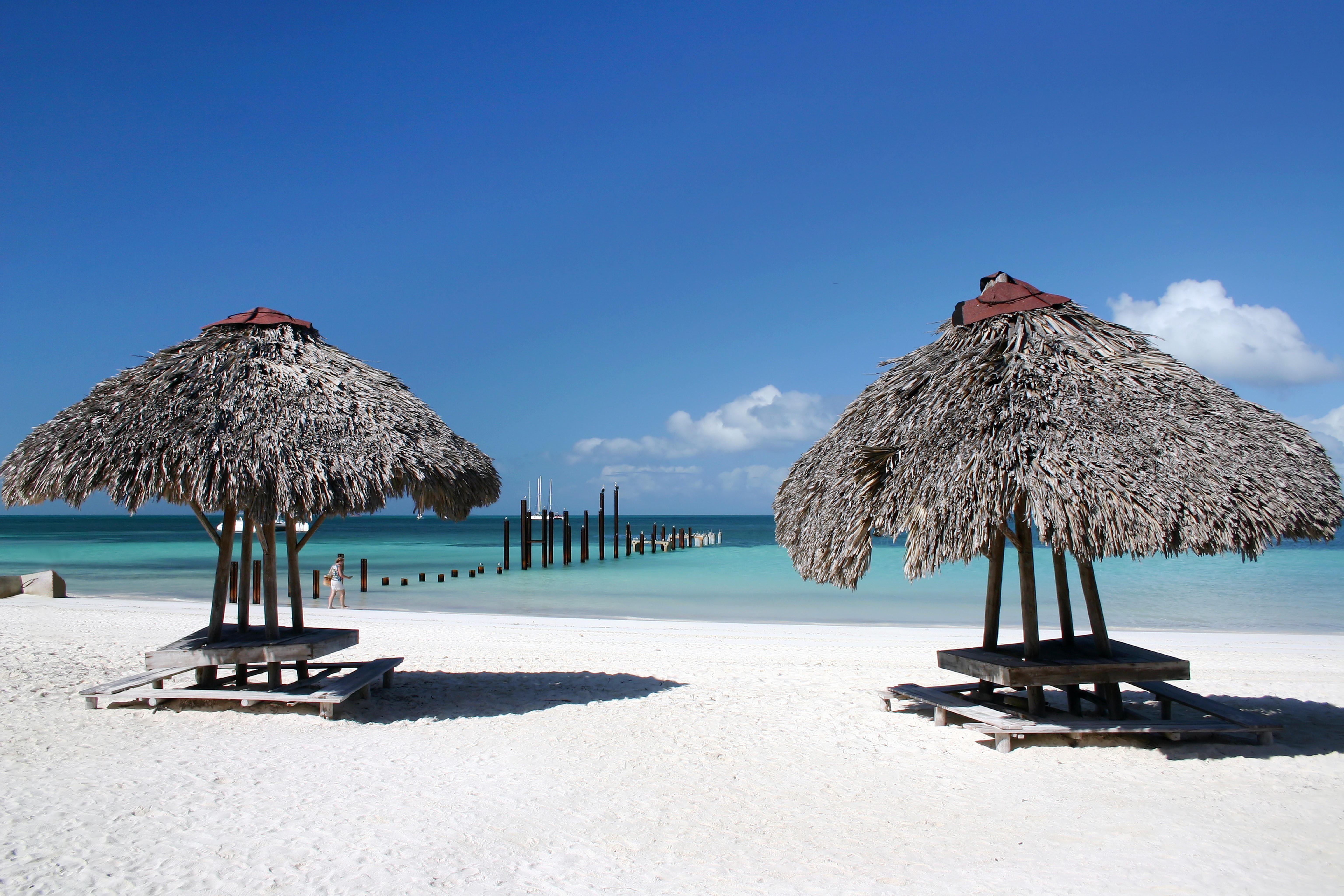 Beach with thatched umbrellas and pier HD Wallpaper